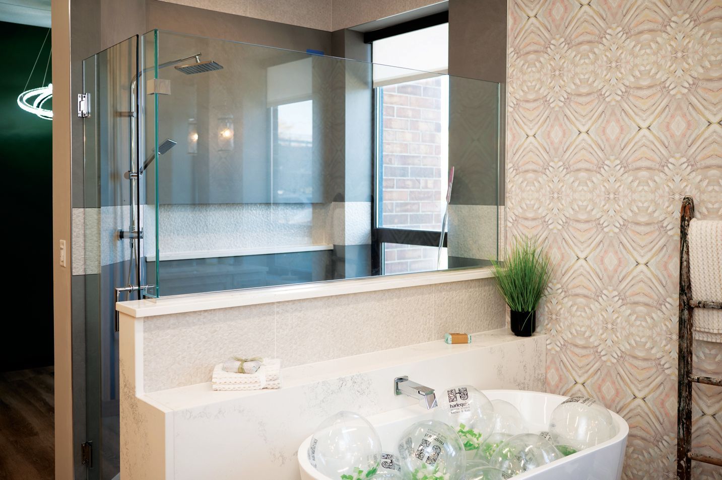 A modern bathroom featuring a white bathtub filled with transparent balloons in front of a glass-enclosed shower.