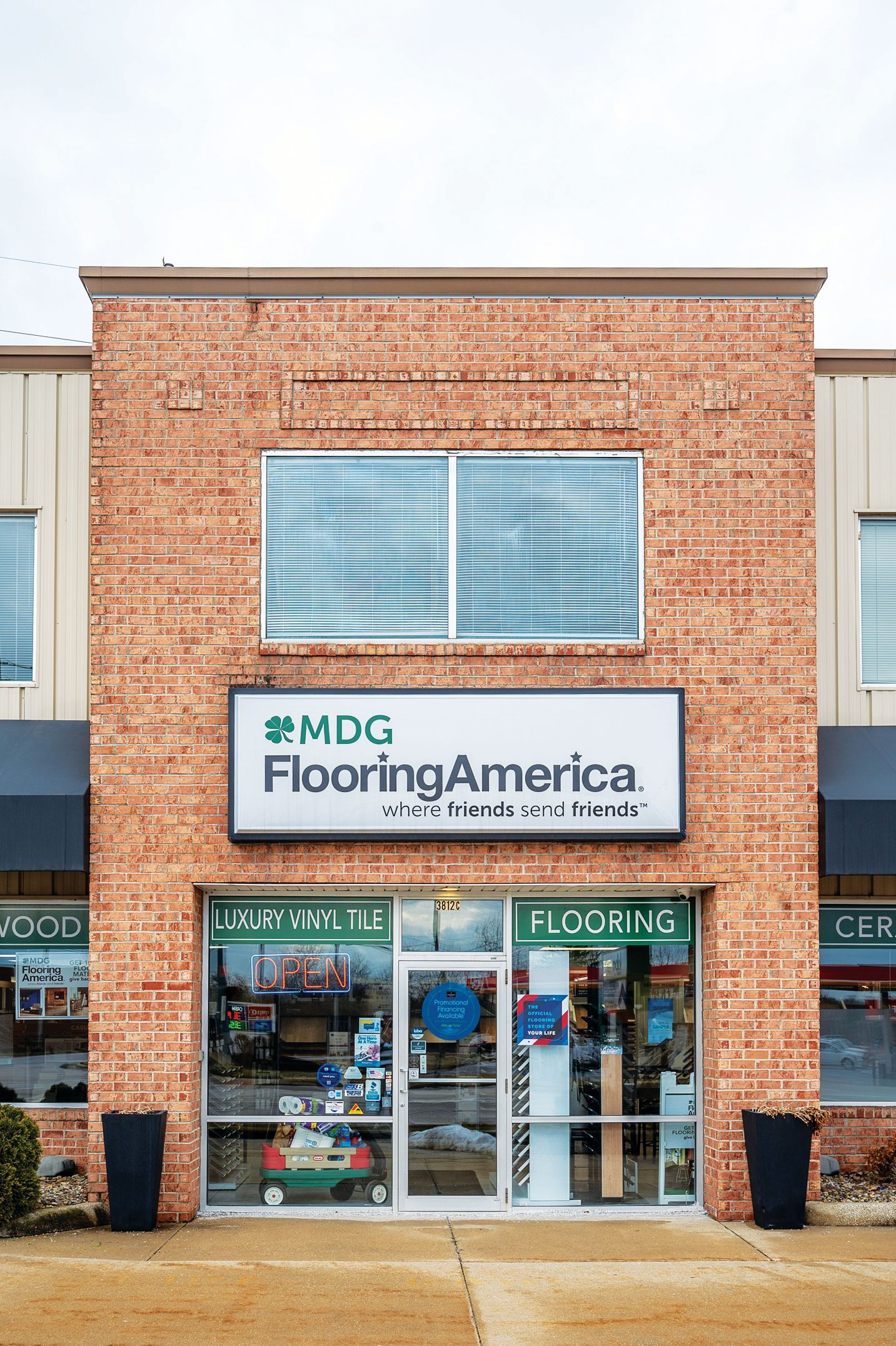 MDG Flooring America storefront with a brick facade, central entrance, and upper window.