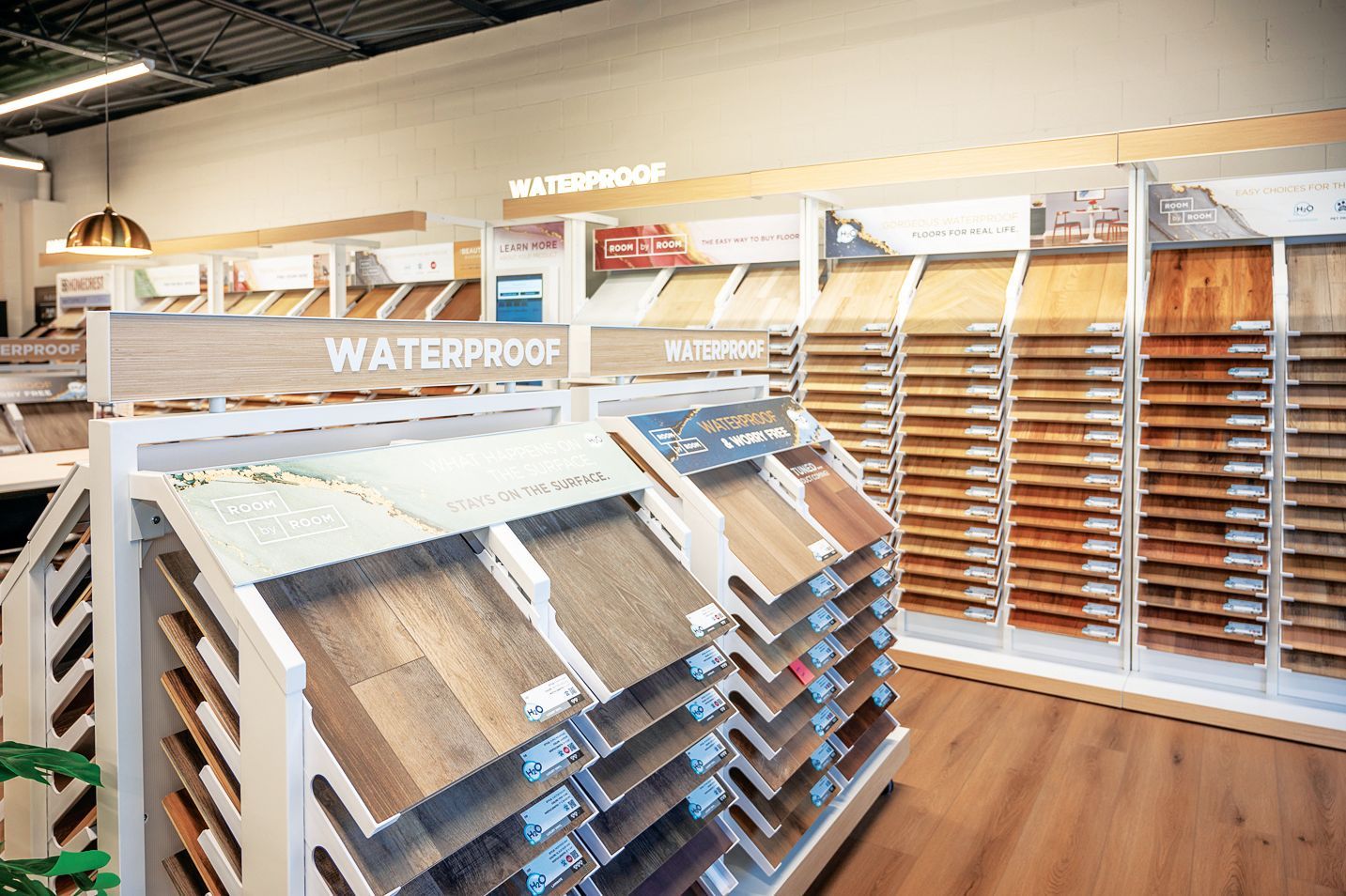 A store display with various wood-look flooring samples on shelves, labeled as waterproof.