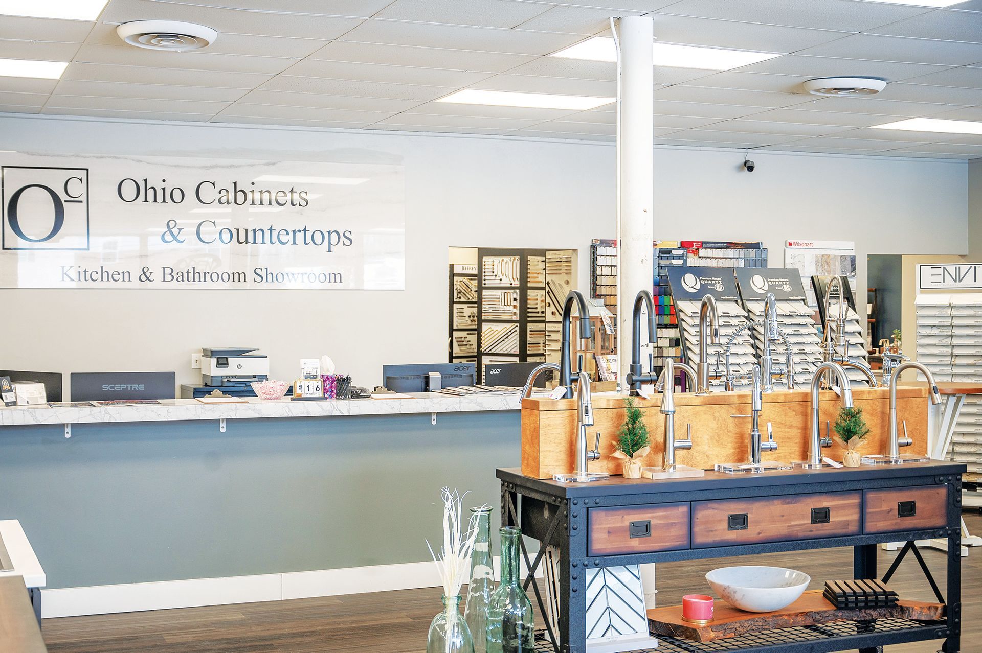 Interior of Ohio Cabinets & Countertops showroom with a service desk and a display table featuring various faucets.