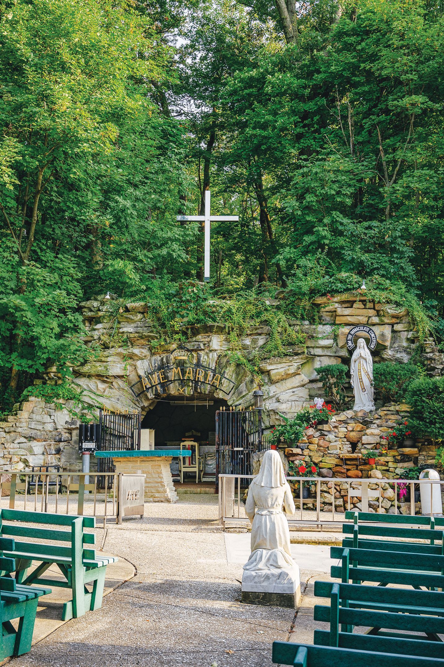A stack of books sits on a wooden table, next to a lit candle and a warm cup of coffee or tea.