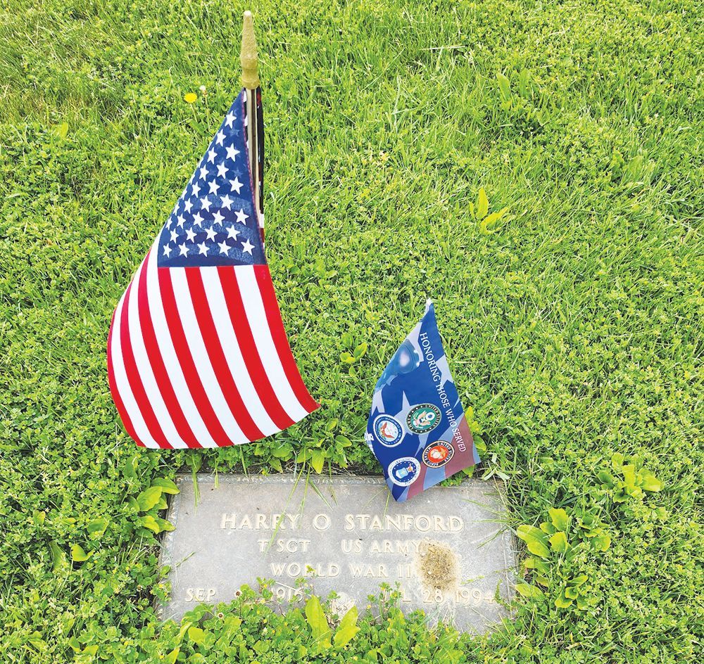Grave marker for Harry O. Stanford, a World War II veteran, displayed in grass with two small American-style flags.