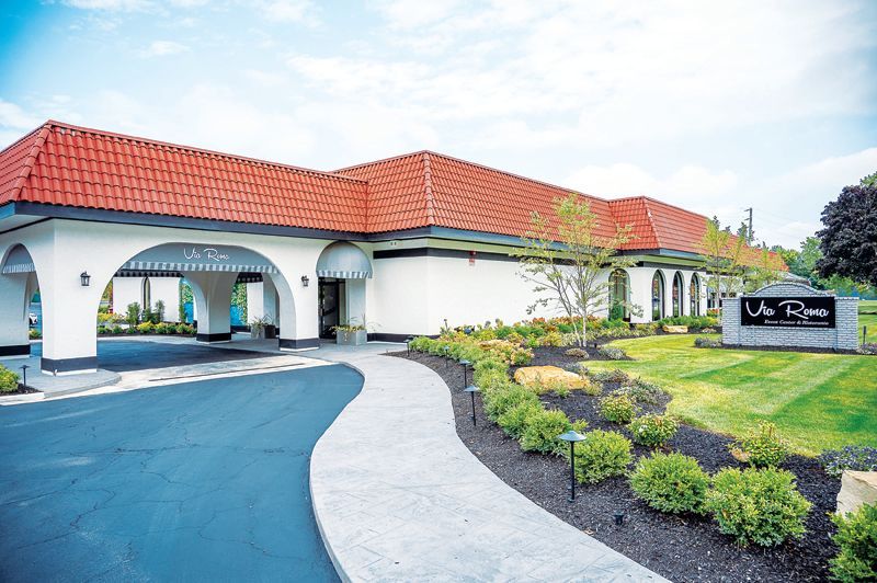 The exterior of La Vera Party Center, featuring a white building with a red-tiled roof, an arched driveway, and landscaping.