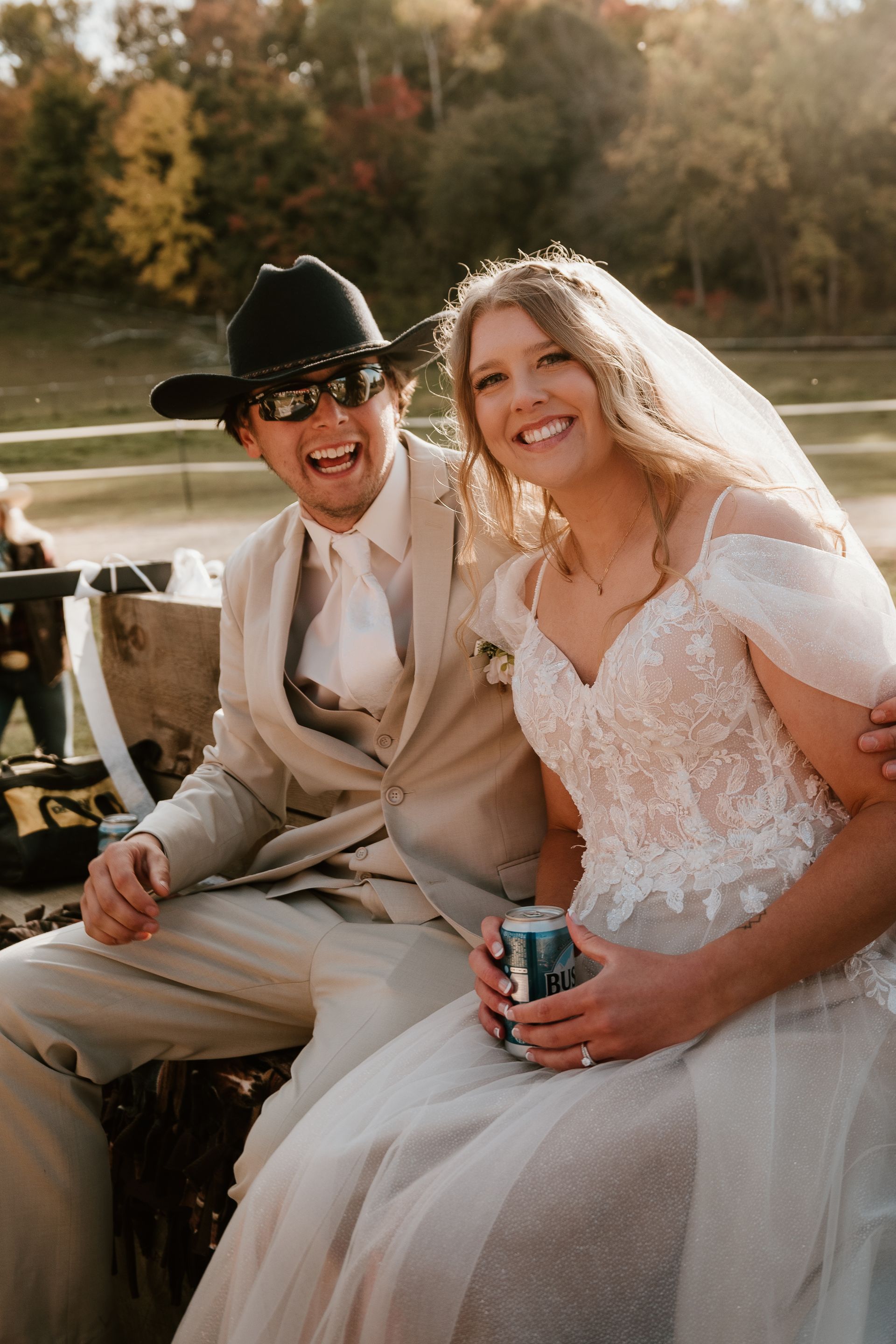 A bride and groom are sitting next to each other on a wagon.