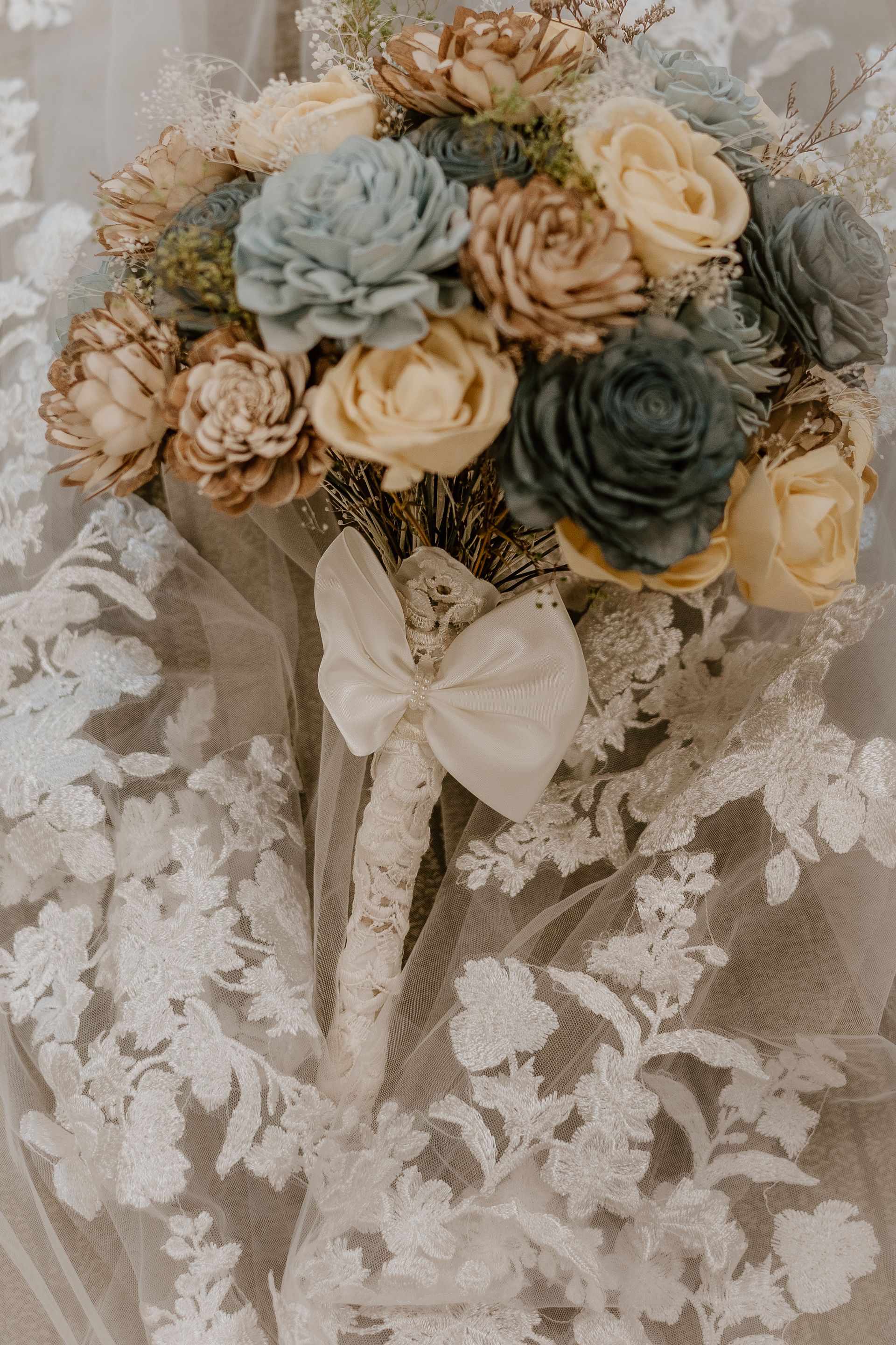 A bouquet of flowers is sitting on top of a white lace dress.