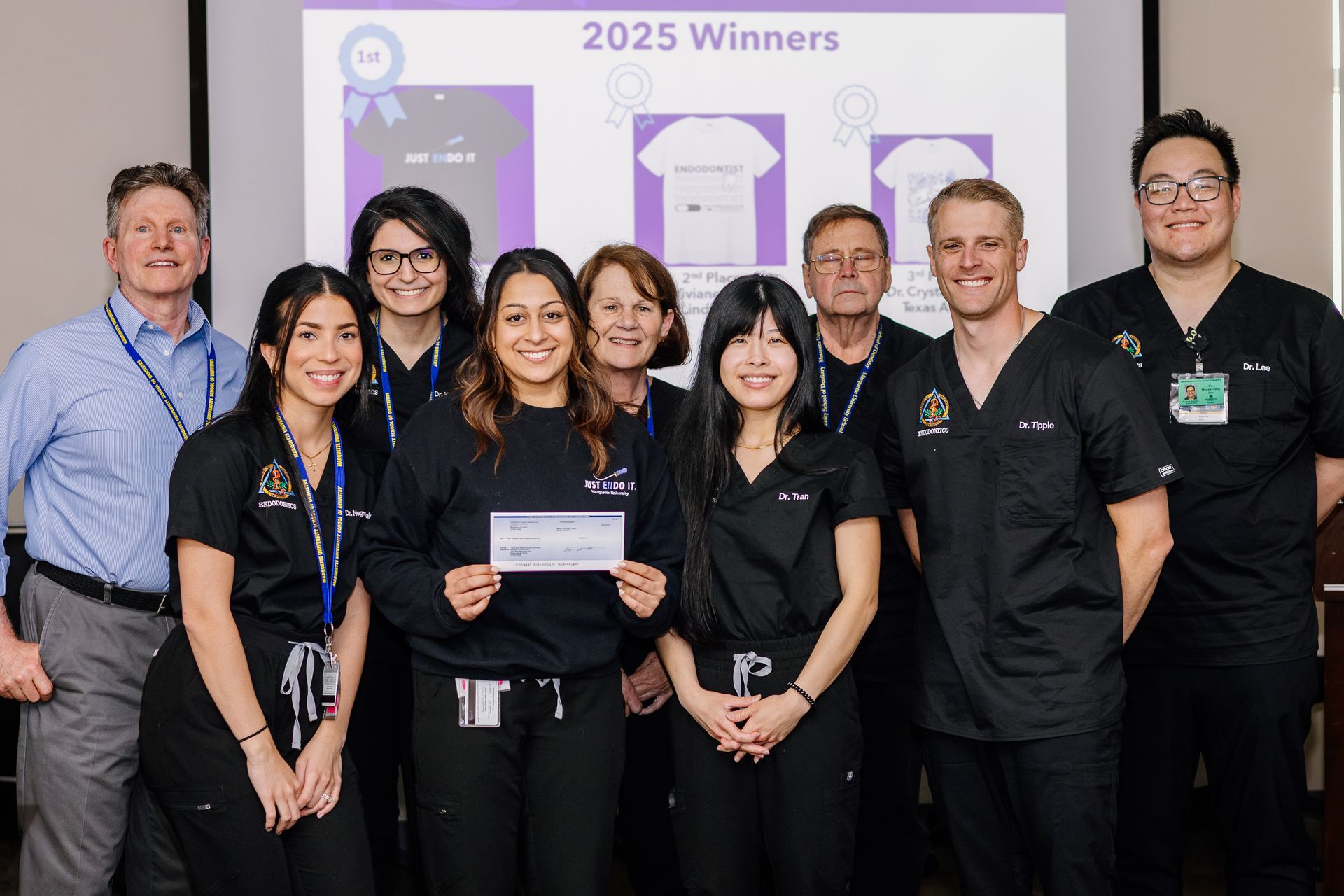 Group of people posing at an awards event in front of a “2025 Winners” display.