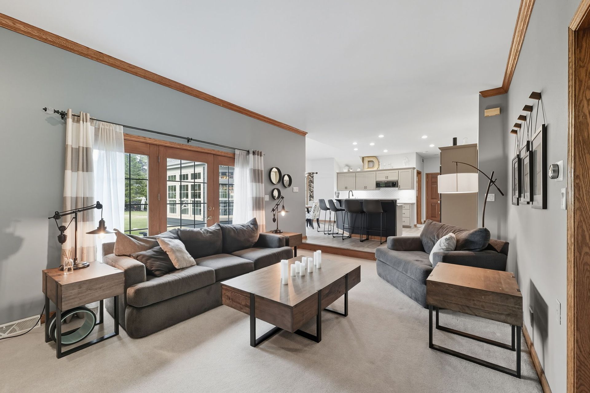 Spacious modern living room with gray sofas, coffee table, fireplace, and large windows with curtains
