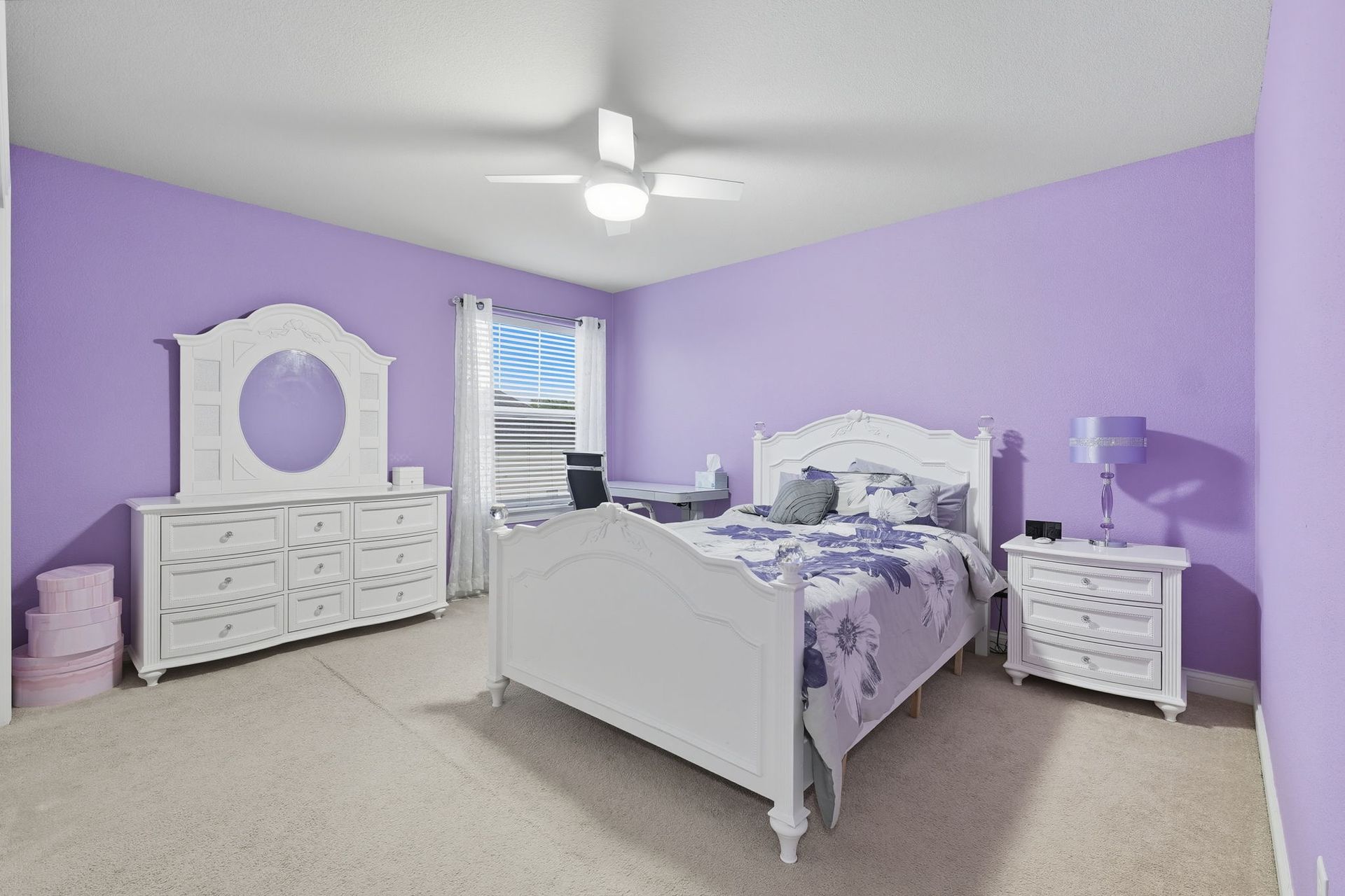 Lavender bedroom with white furniture, a bed, dresser, and nightstands under a ceiling fan.