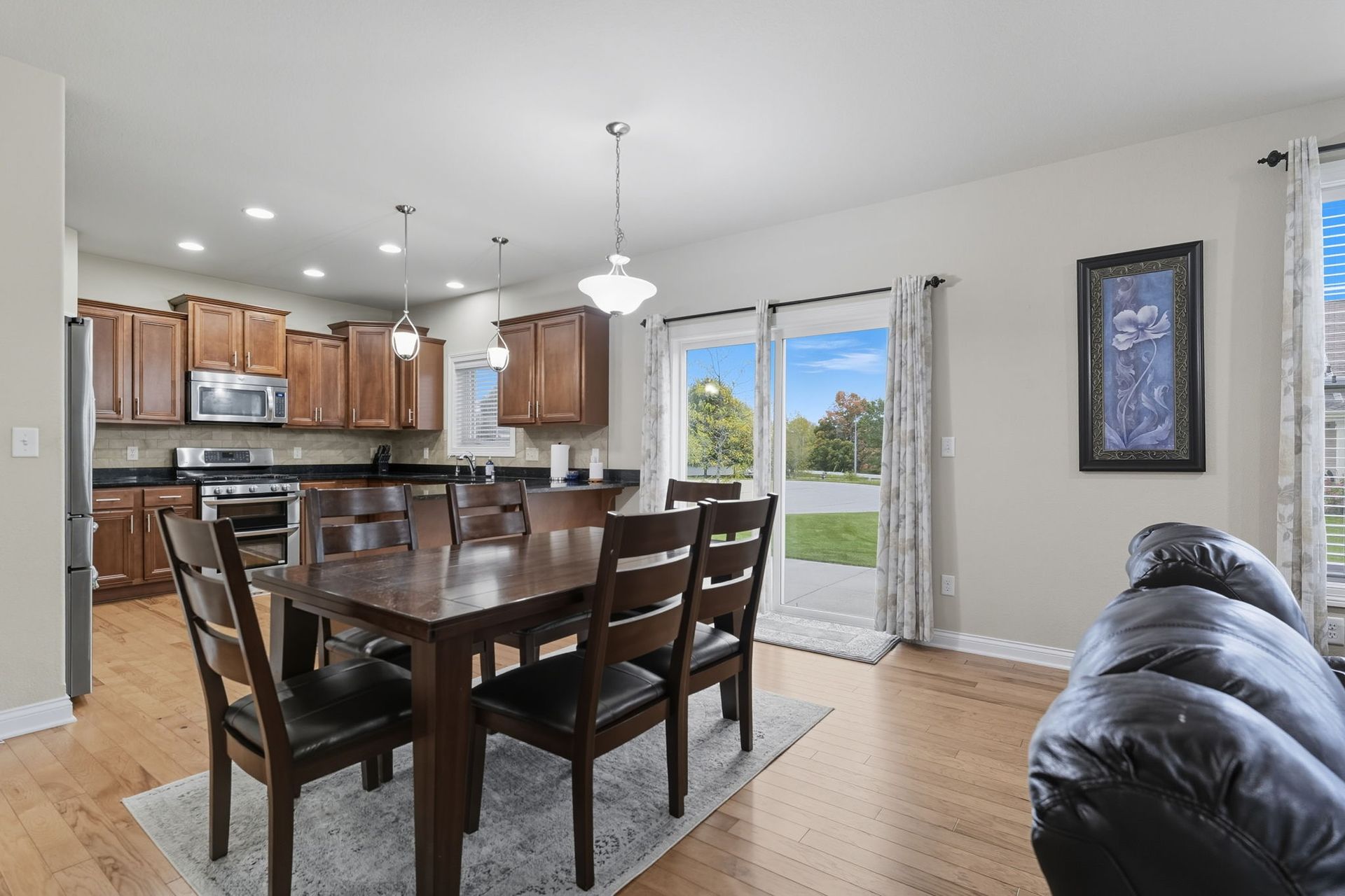 Open dining and kitchen area with wooden table, black chairs, and sliding glass door to a backyard.