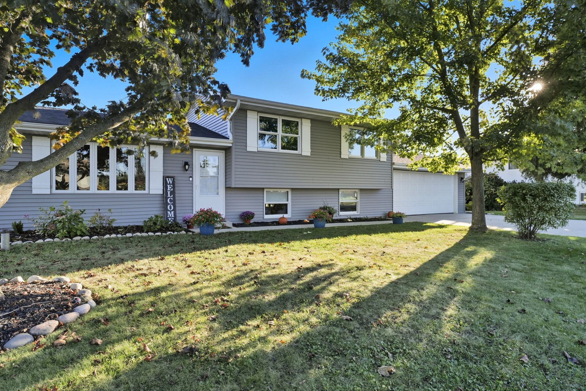 Suburban house with a front yard, trees, and long afternoon shadows