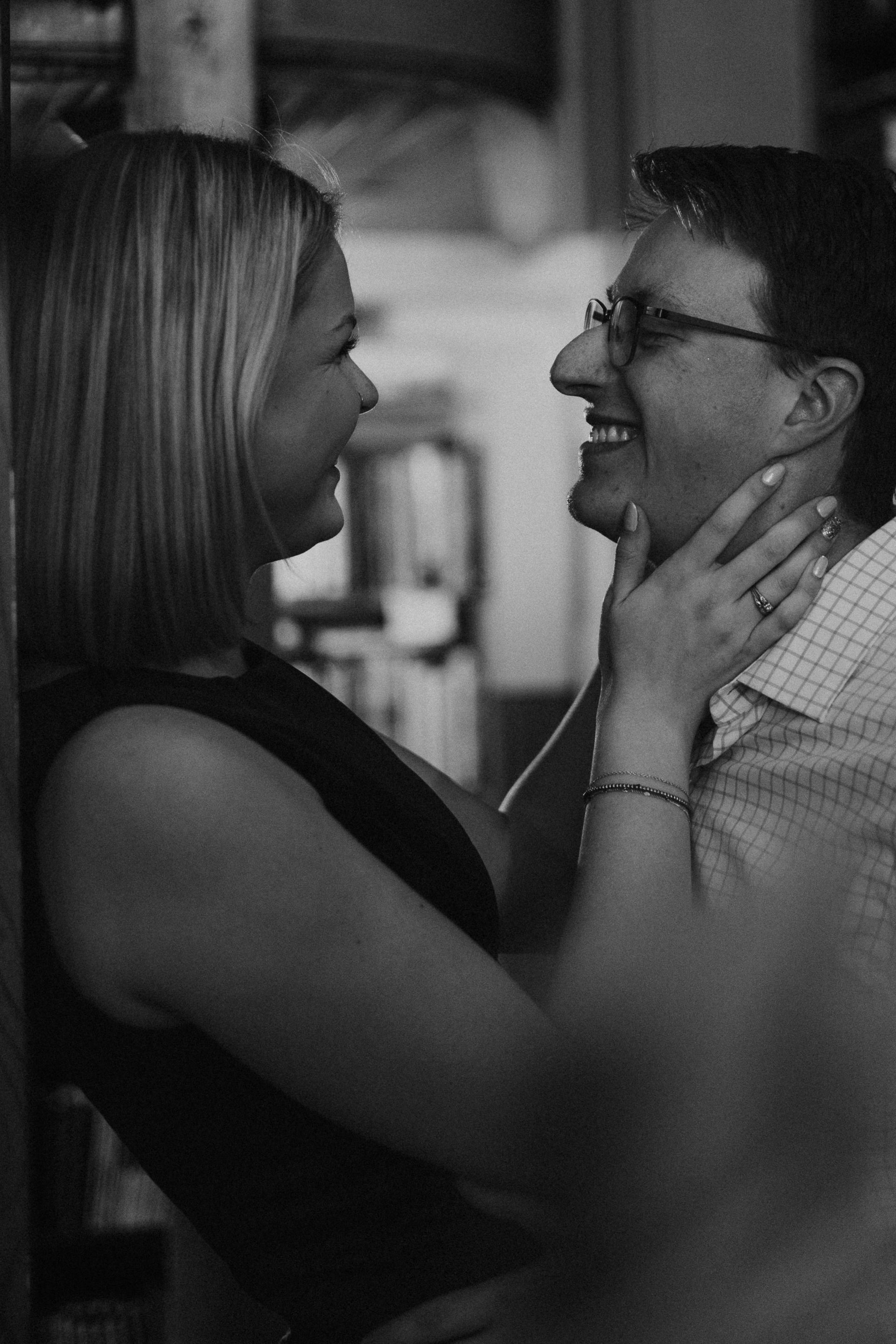 Two people smiling and holding each other’s faces in a close, black-and-white portrait.