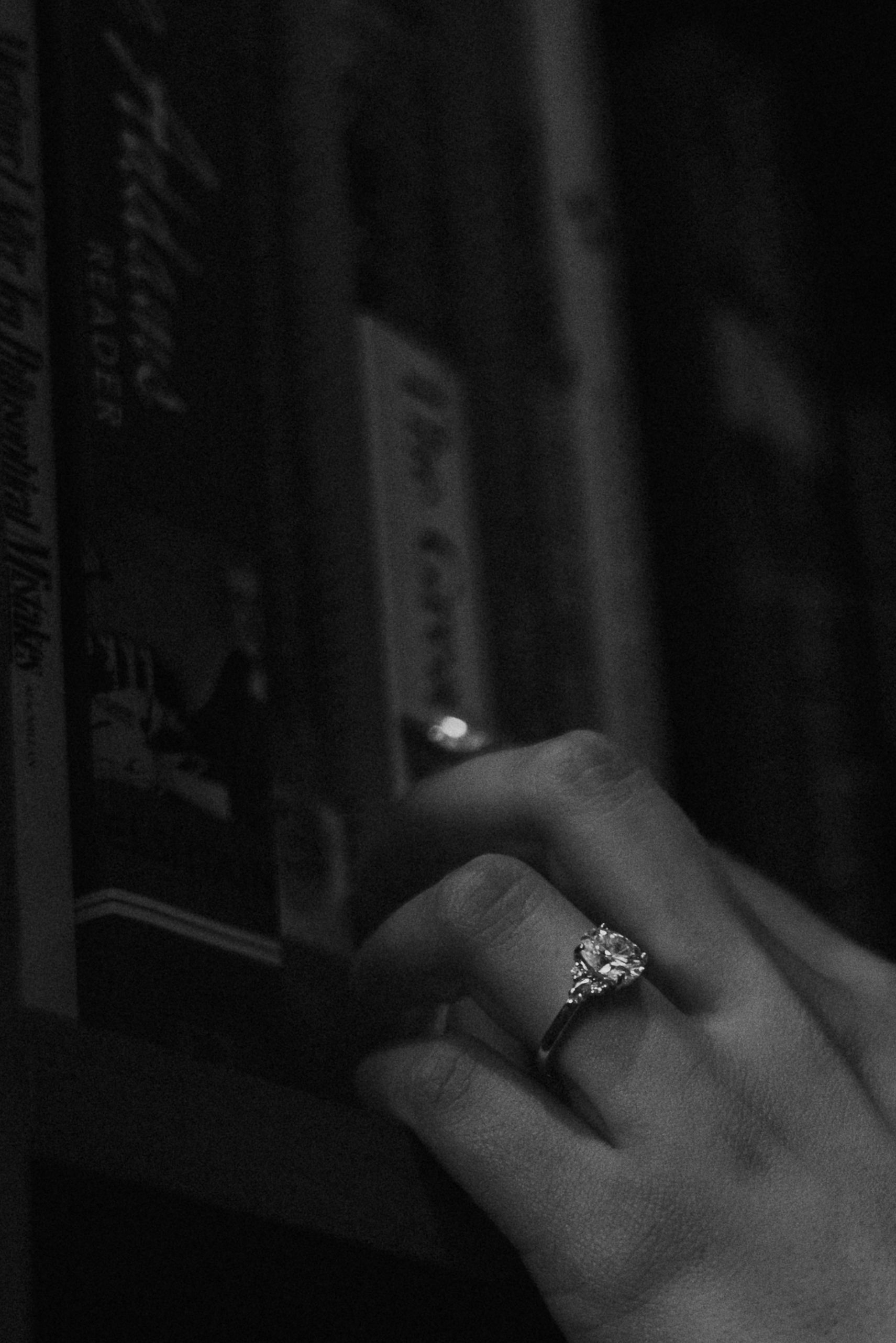 Hand with a ring touching books in dim black-and-white light