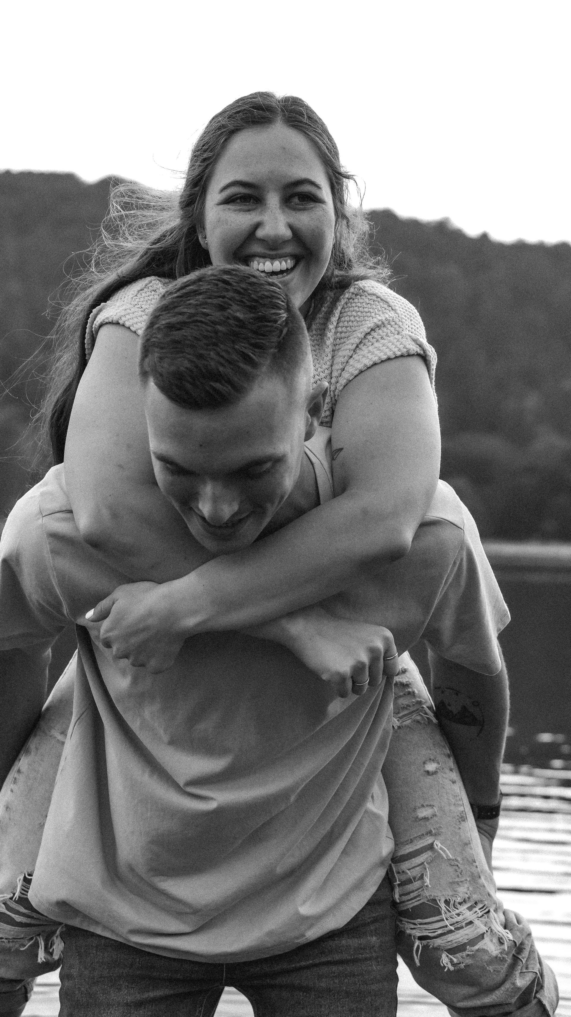 A man is carrying a woman on his back in a black and white photo.