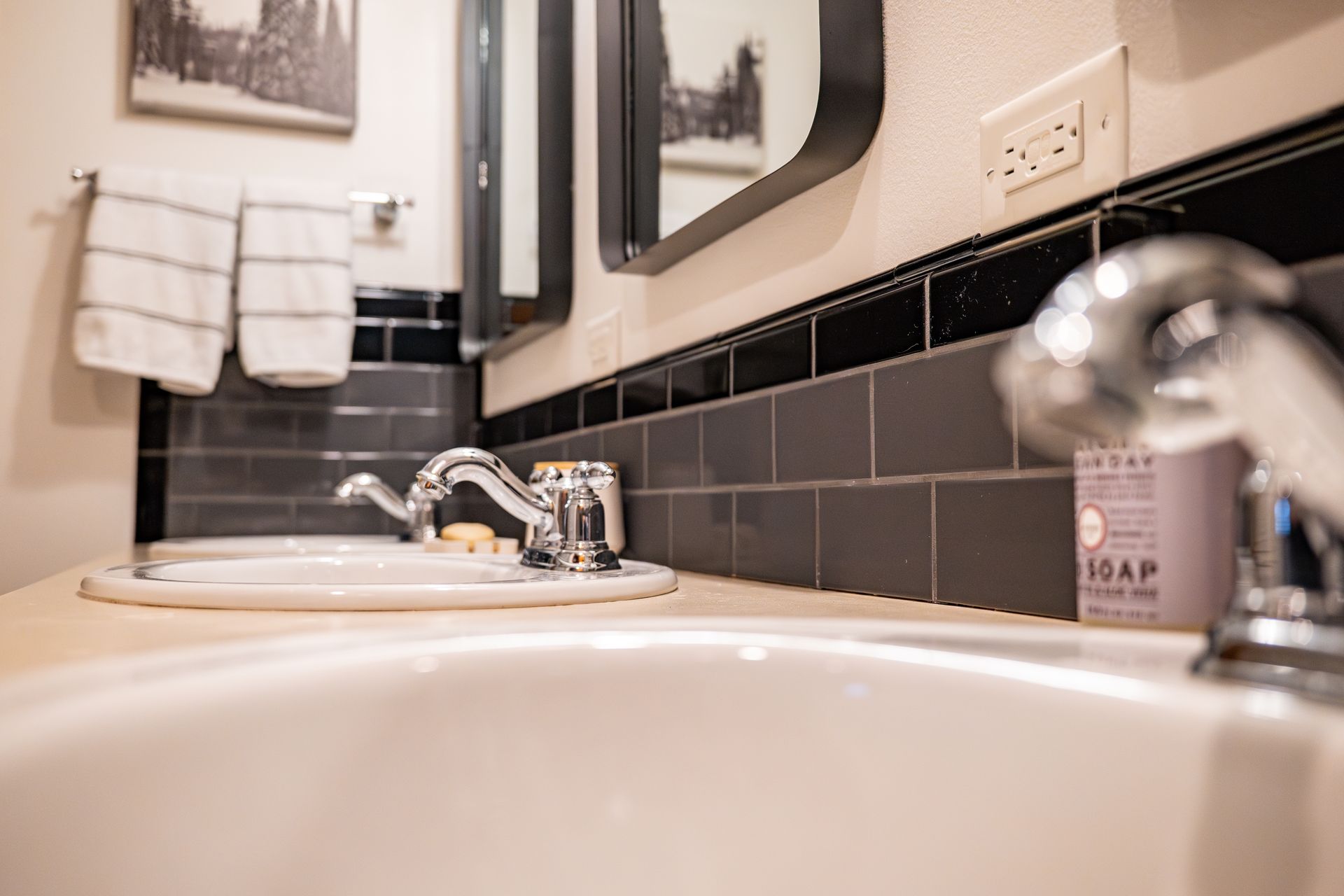 A bathroom with a sink , mirror and soap dispenser.