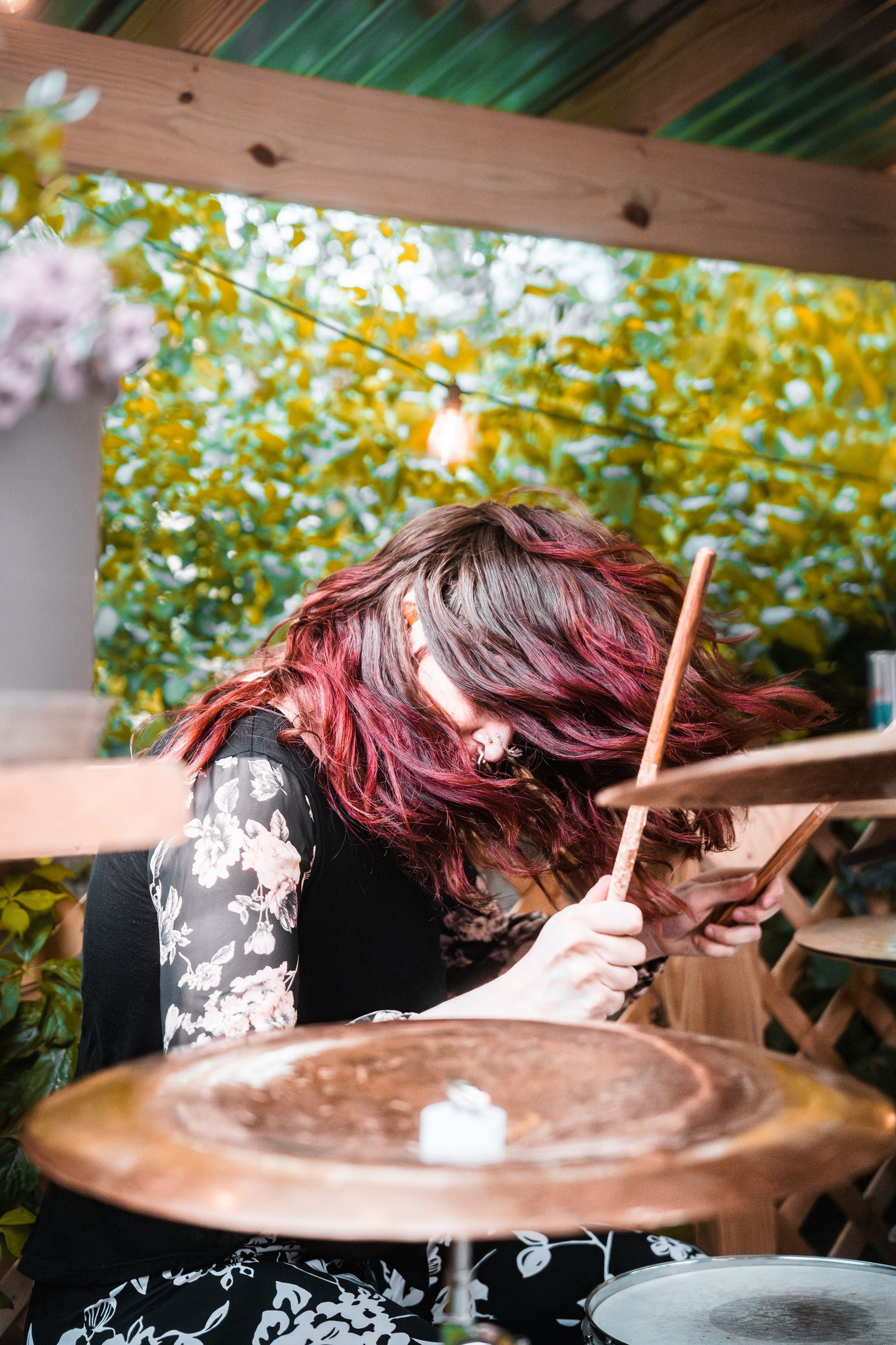 A woman with red hair is playing a drum set.