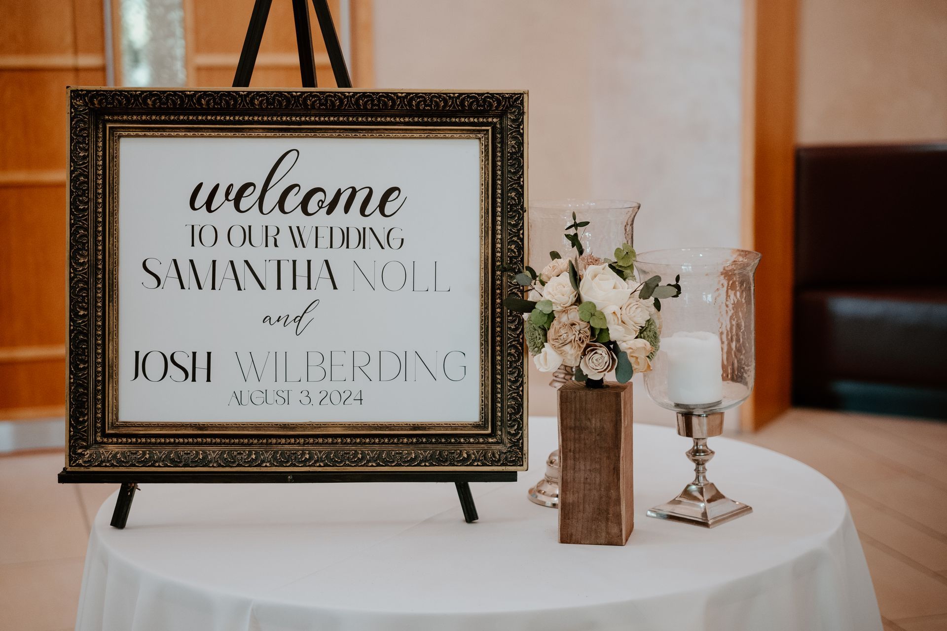 Welcome sign on easel beside white floral arrangement on a table at a wedding reception