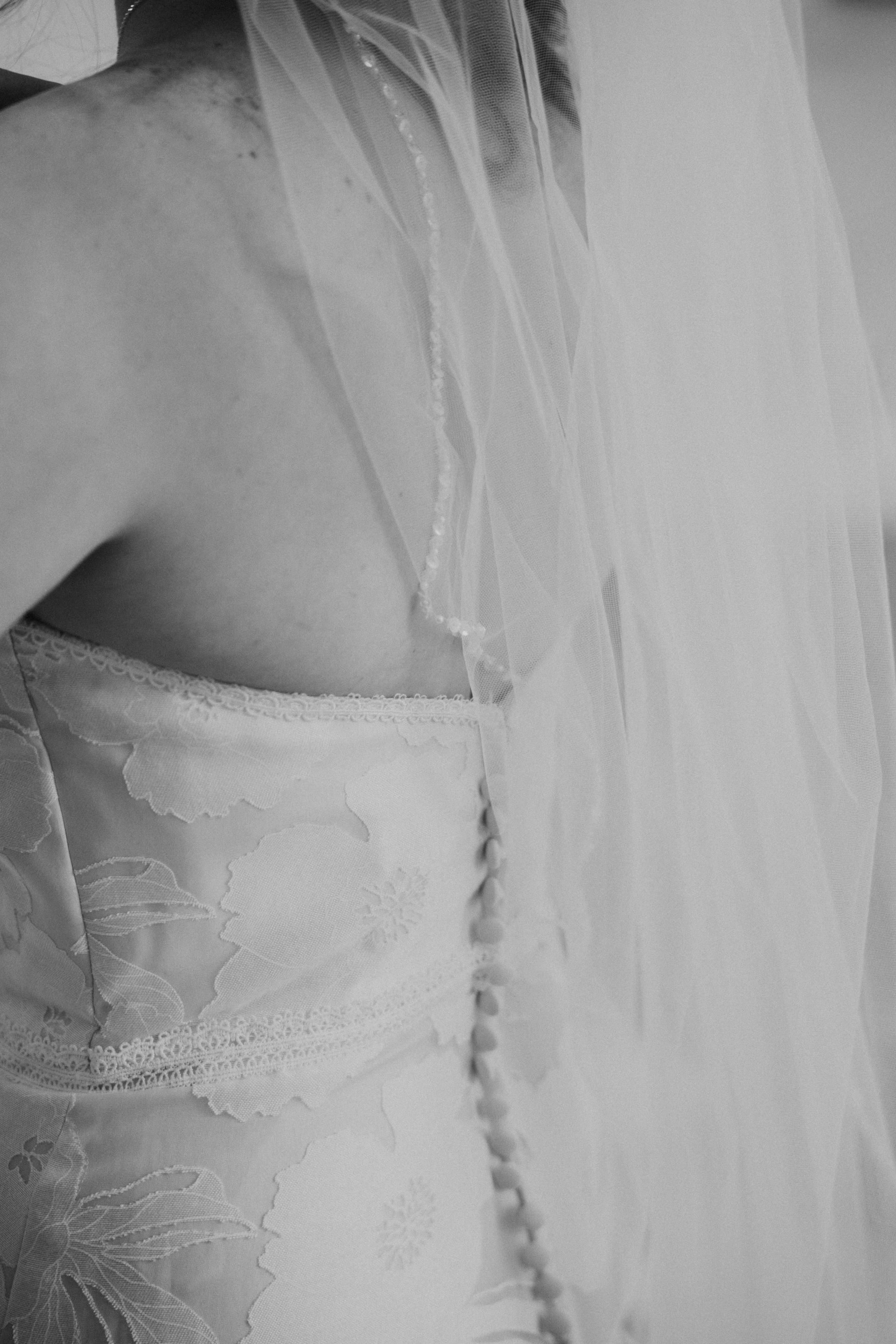 Close-up of a white lace dress with veil or sheer fabric draped over it