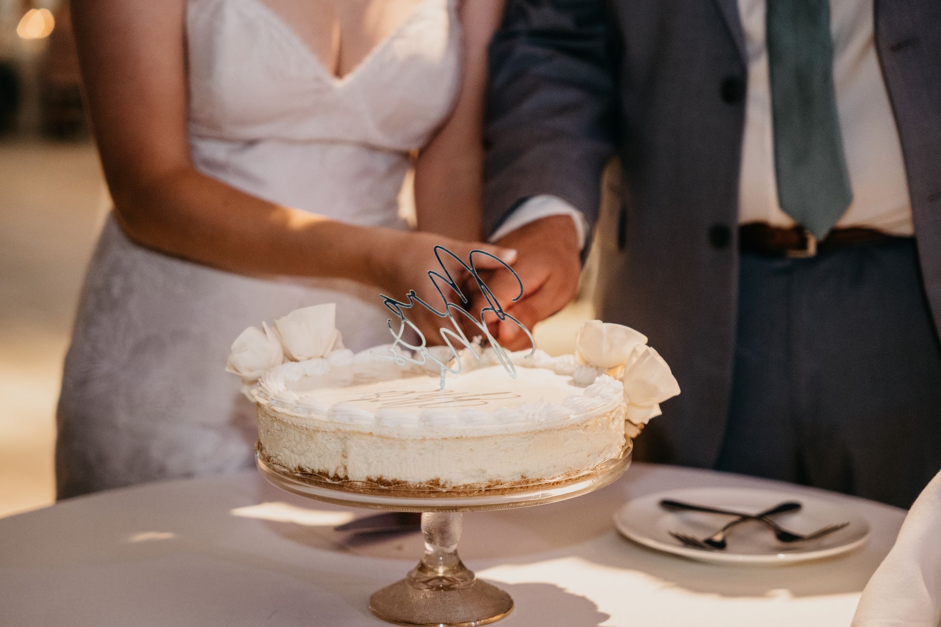 Bride and groom cutting a white wedding cake together at a reception table