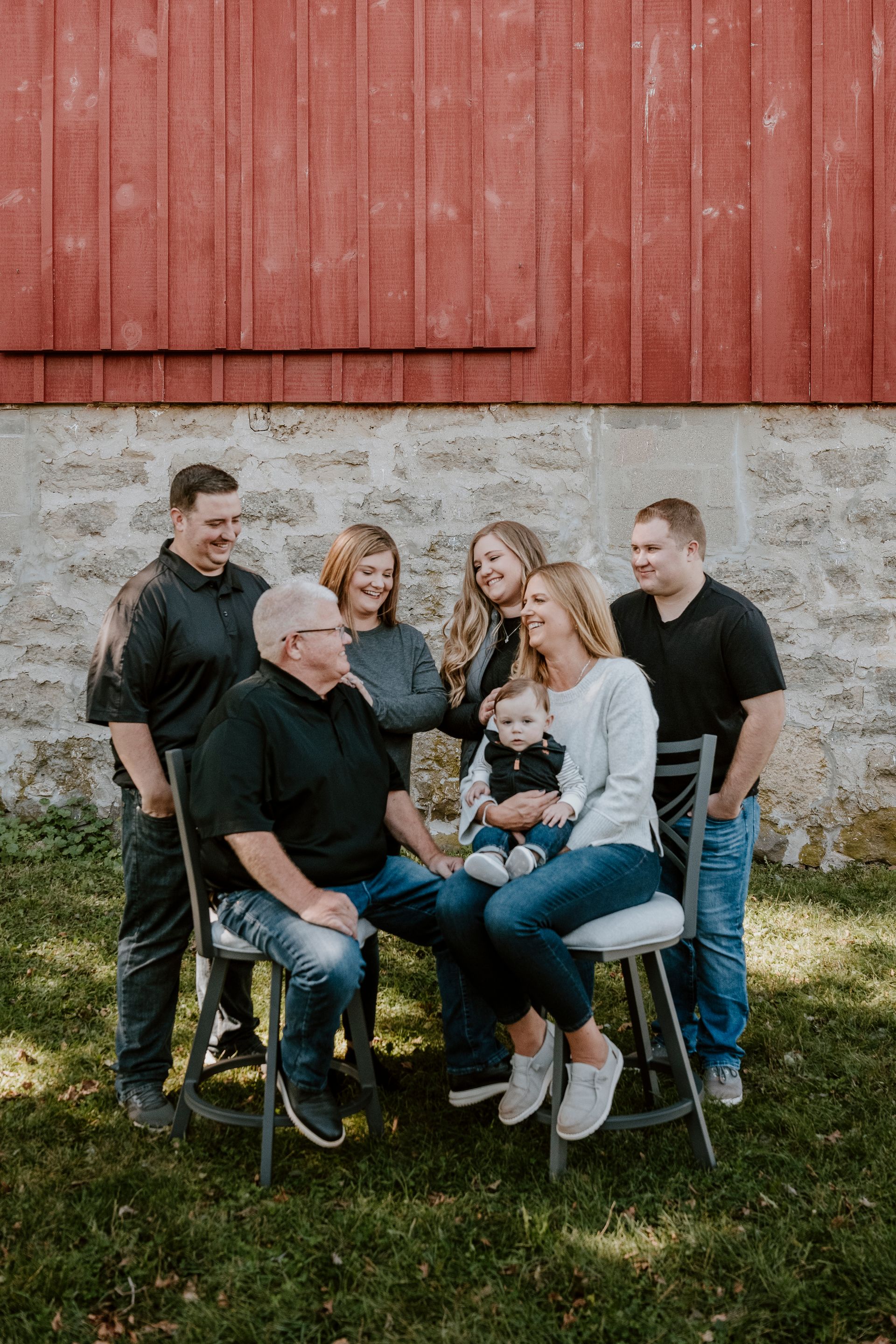 A family is posing for a picture in front of a red barn.