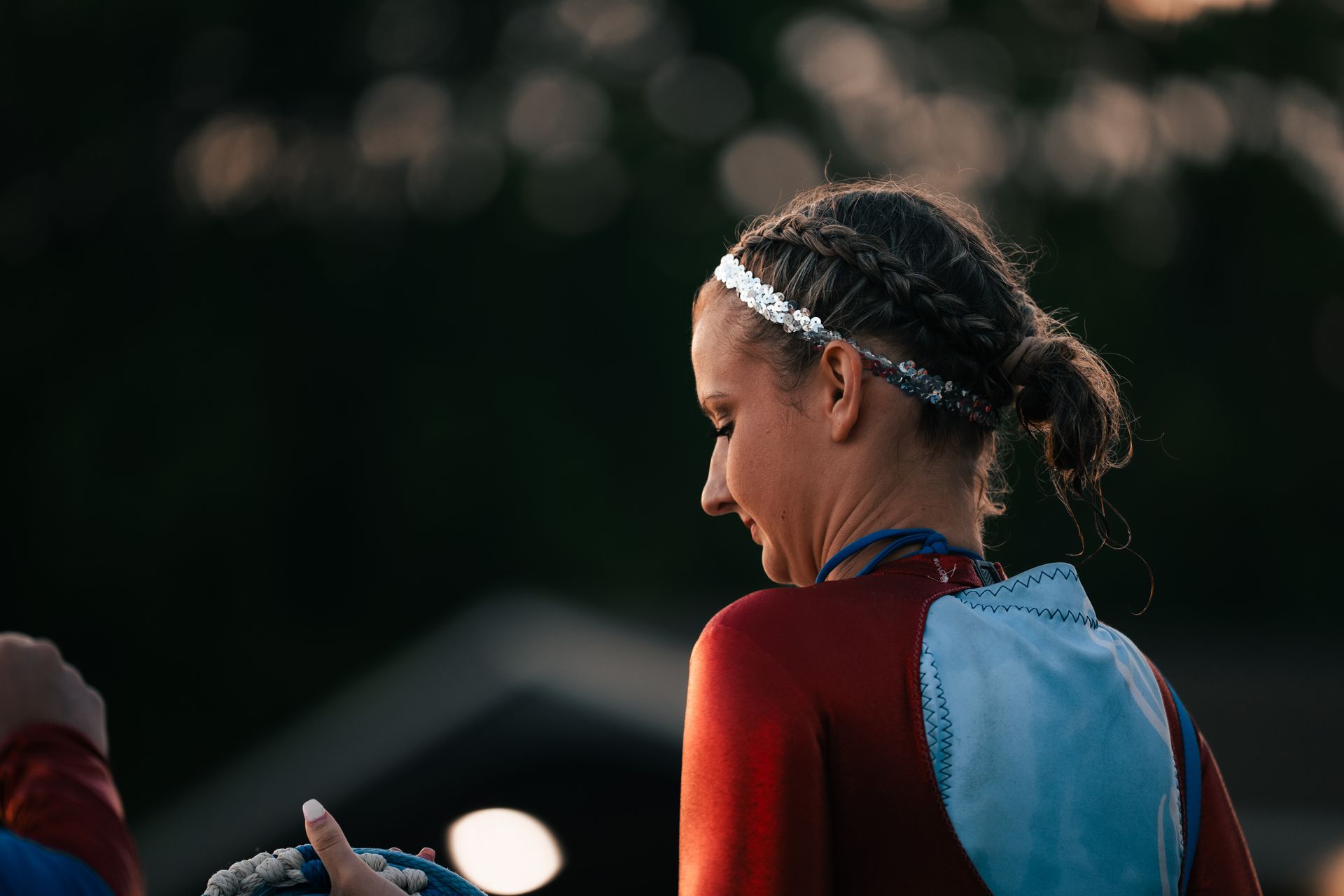 Athlete in a red and blue racing suit looking down under stadium lights