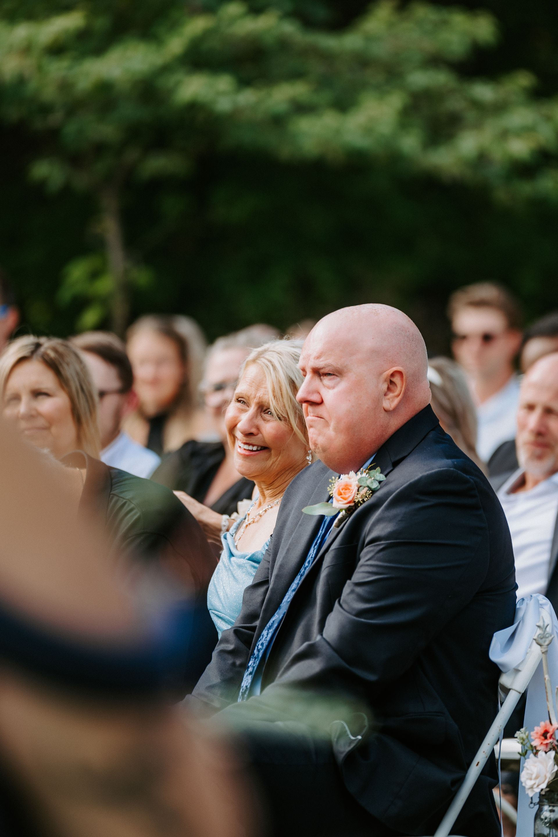 Guests seated outdoors at a wedding ceremony, watching attentively.