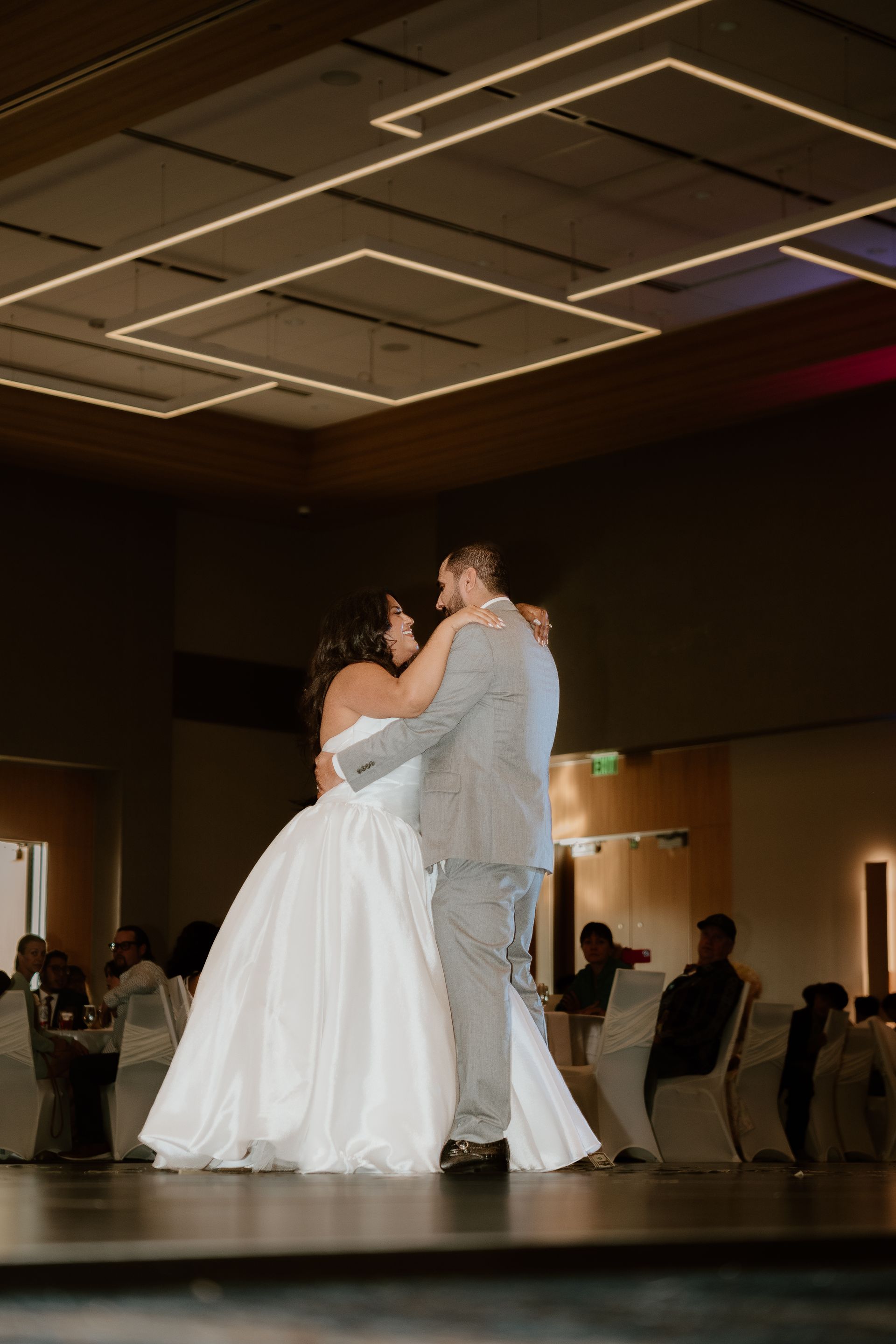 Bride and groom slow dancing at a wedding reception under warm ceiling lights