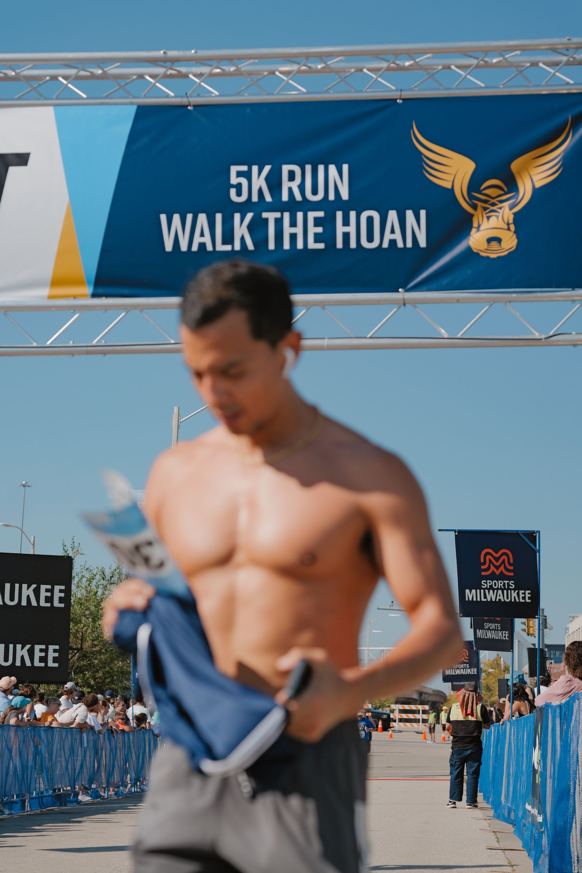 Runner crossing finish line beneath “5K Run Walk The Huan” banner at a race event