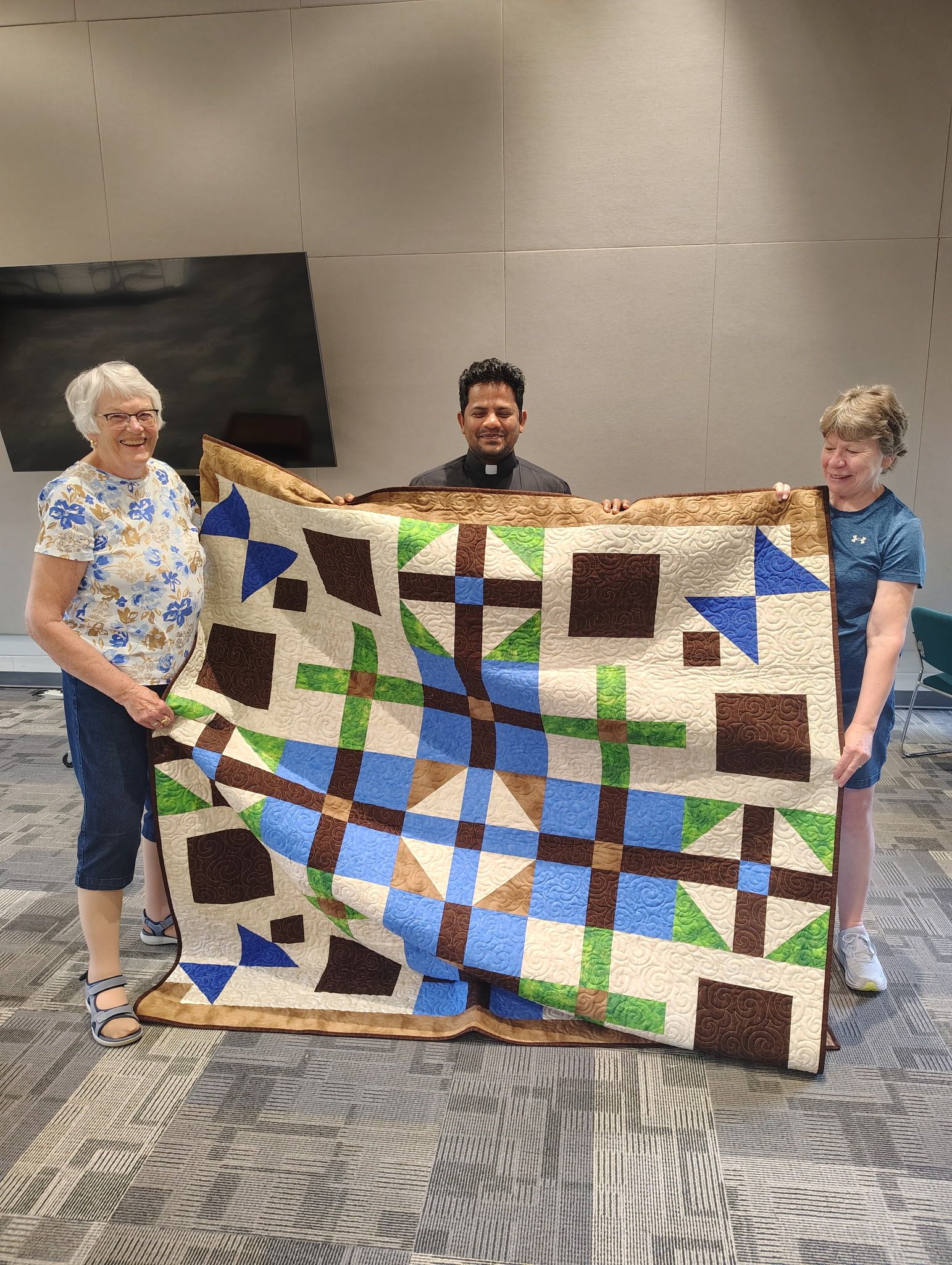 Father Yesu receiving a quilt from the Simple Stitches.