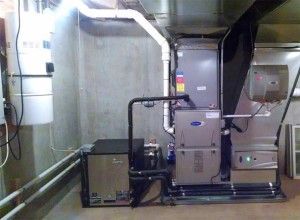 Industrial HVAC system with large gray furnace, ducts, and pipes in a utility room