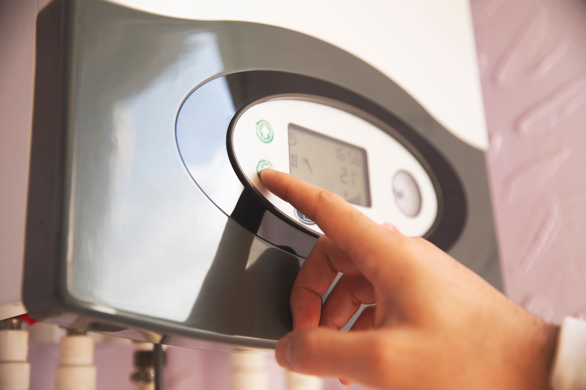 Hand turning a control knob on a gray wall-mounted thermostat or heater display