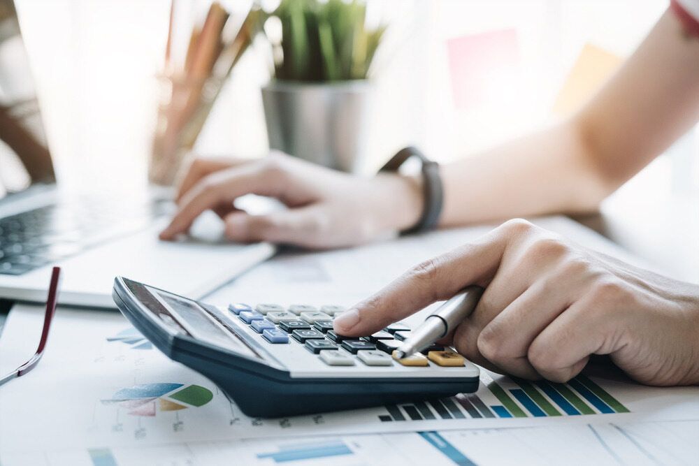 A Person Is Using a Calculator at A Desk — Blue Orchid Accounting In Woongarrah, NSW
