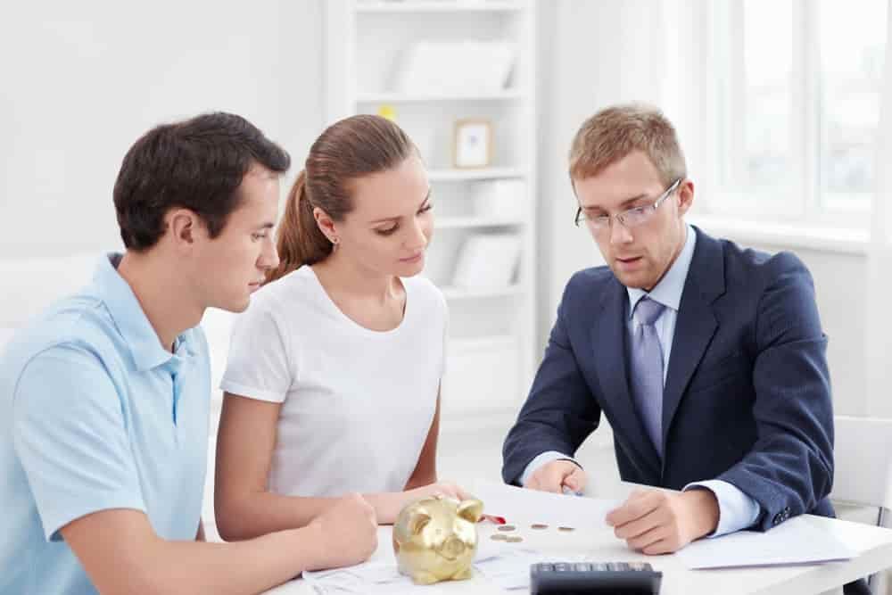 A Man and A Woman Are Sitting at A Table Talking to A Man in A Suit — Blue Orchid Accounting In Woongarrah, NSW