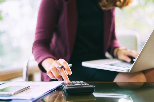 A Woman Is Using a Laptop and A Calculator at The Same Time — Blue Orchid Accounting In Woongarrah, NSW
