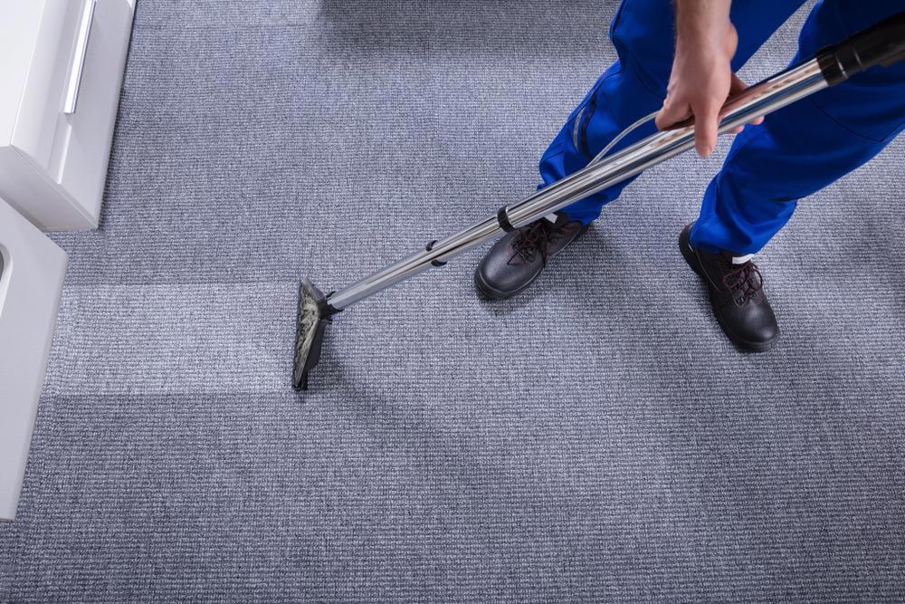 Cleaner in Protective Clothing Performing Carpet Cleaning