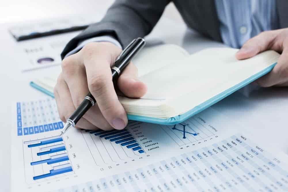 A Person Is Writing in A Notebook with A Pen  — Blue Orchid Accounting In Woongarrah, NSW