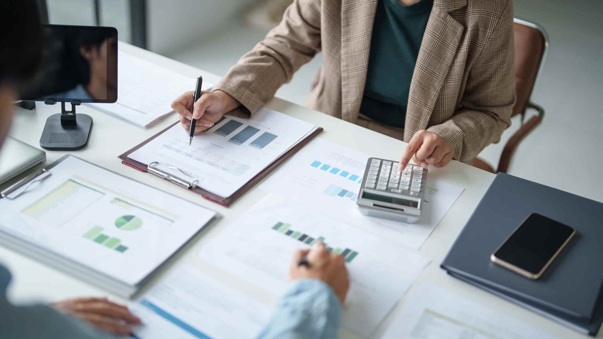 A Woman Is Sitting at A Table Using a Calculator  — Blue Orchid Accounting In Woongarrah, NSW