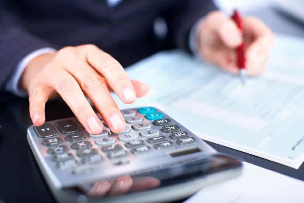 A Person Is Using a Calculator and Writing on A Piece of Paper — Blue Orchid Accounting In Woongarrah, NSW