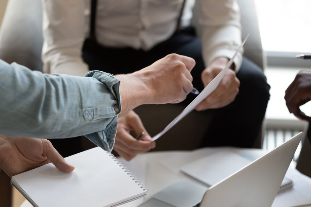 A Man Is Sitting at A Desk with A Calculator and A Cell Phone — Blue Orchid Accounting In Woongarrah, NSW