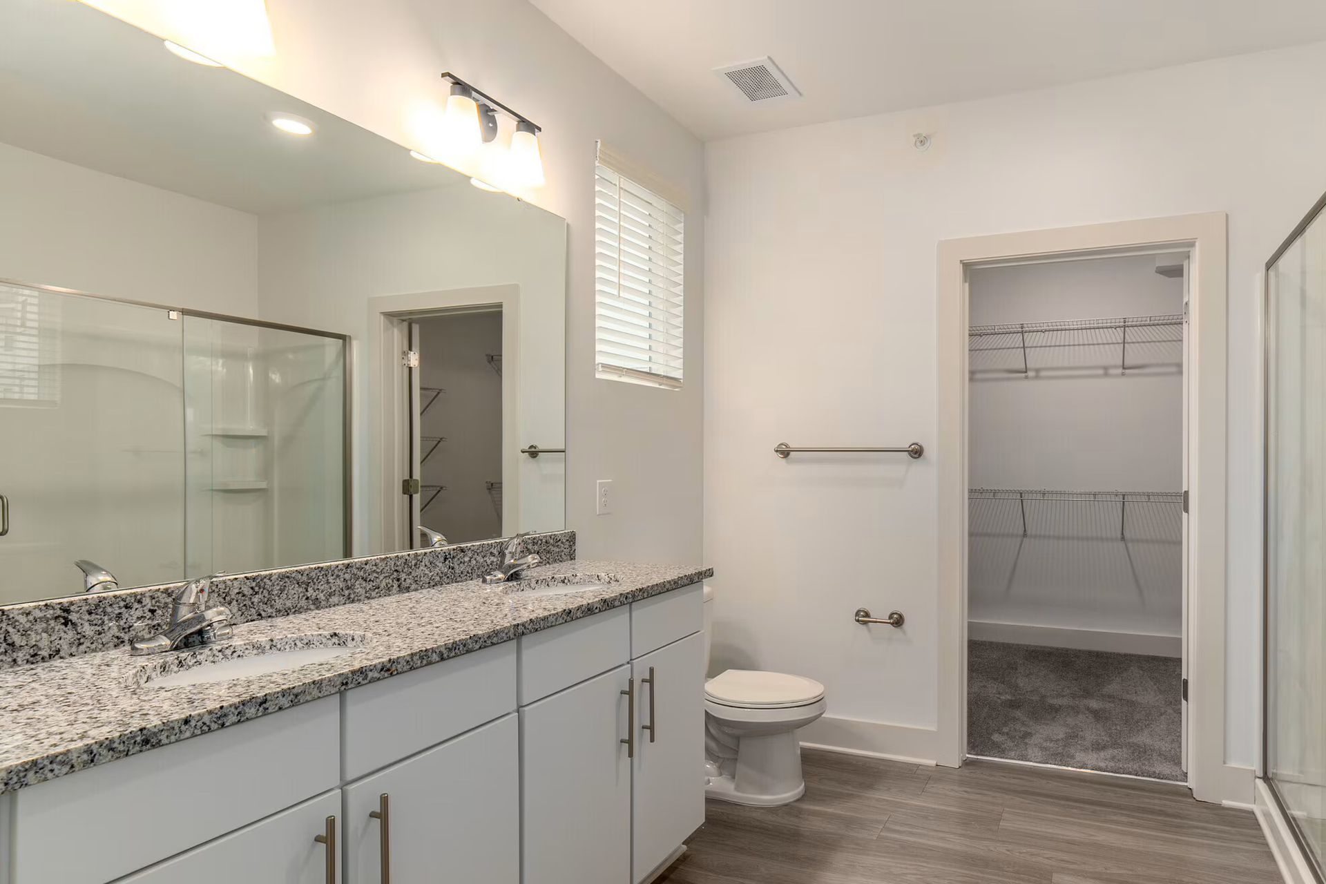 Modern white bathroom with vanity, toilet, and gray flooring.