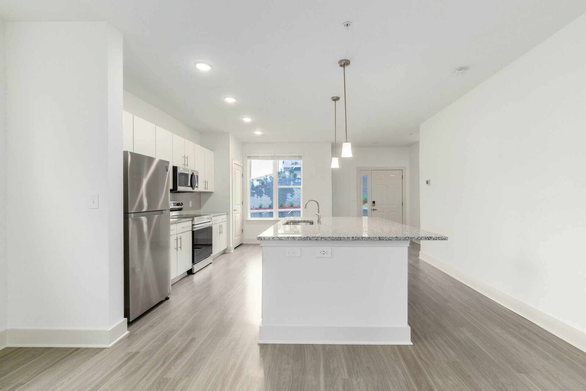 Modern, bright kitchen with white cabinets, stainless steel appliances, and a granite island.