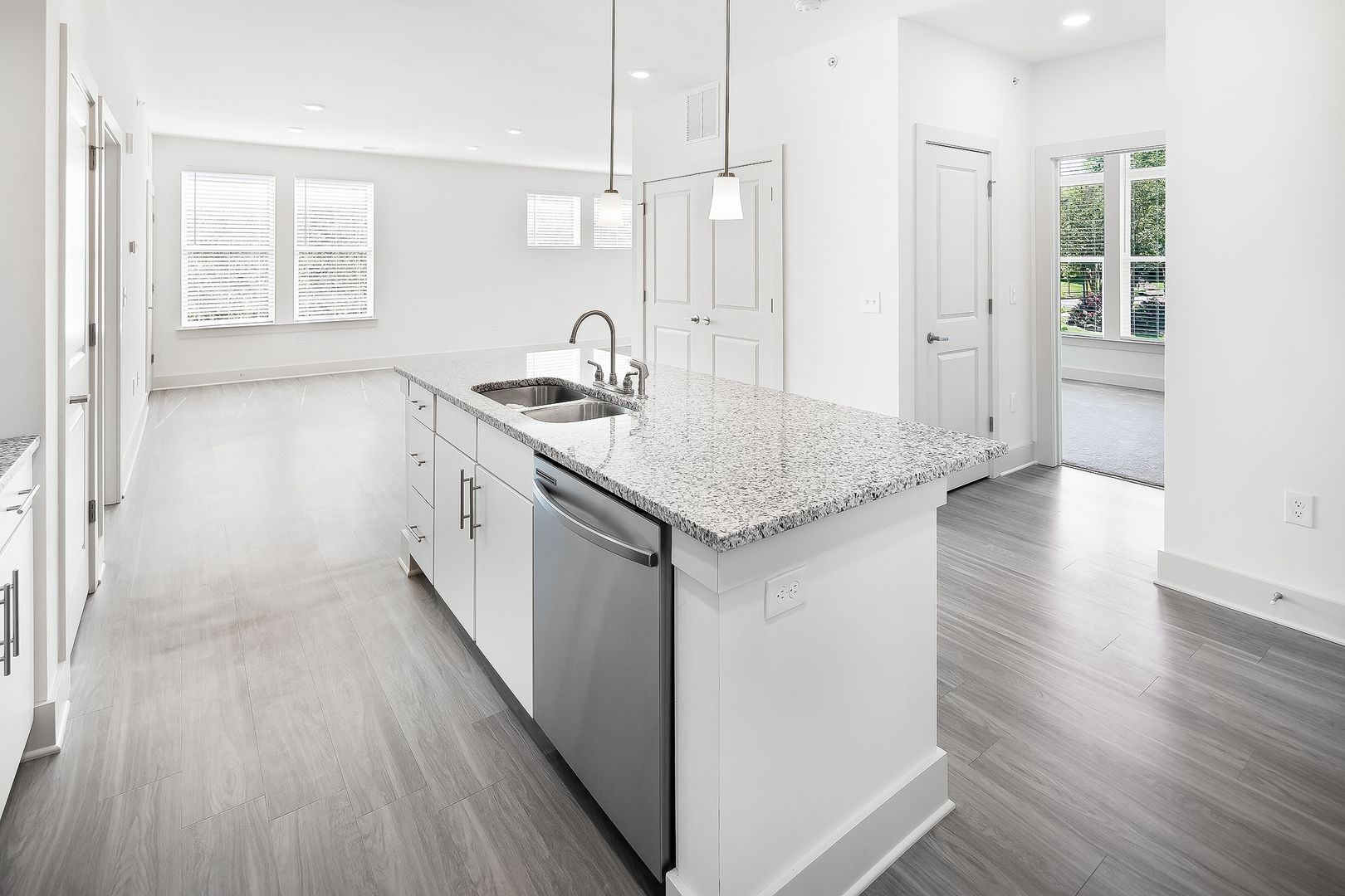 Modern kitchen with white cabinets, granite island, stainless steel appliances, and hardwood floors.