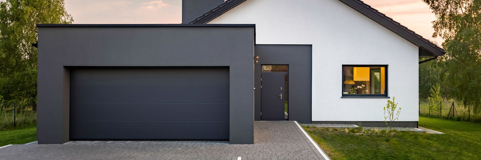 Modern two-tone house with a dark gray garage and white exterior at dusk