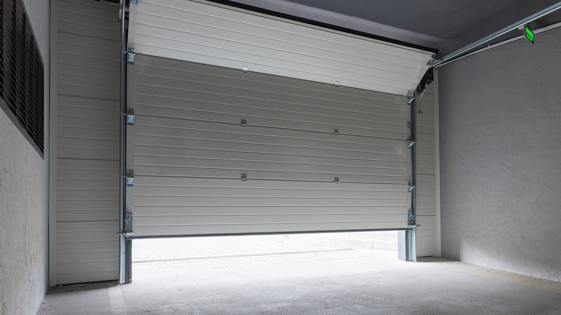 Closed gray roll-up garage door inside an empty industrial space