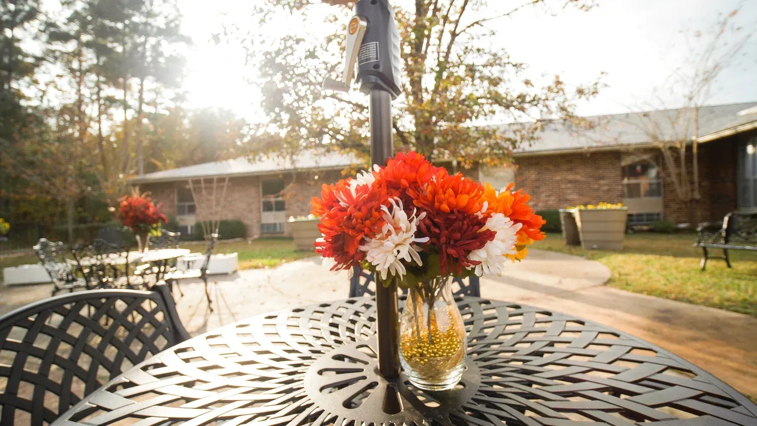 Bouquet of red, white, and orange flowers in a vase on an outdoor patio table at sunset