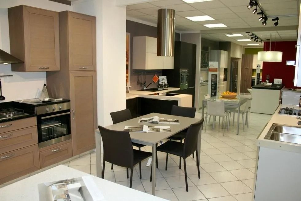Showroom di cucine con vari stili di mobili, elettrodomestici e tavoli da pranzo.