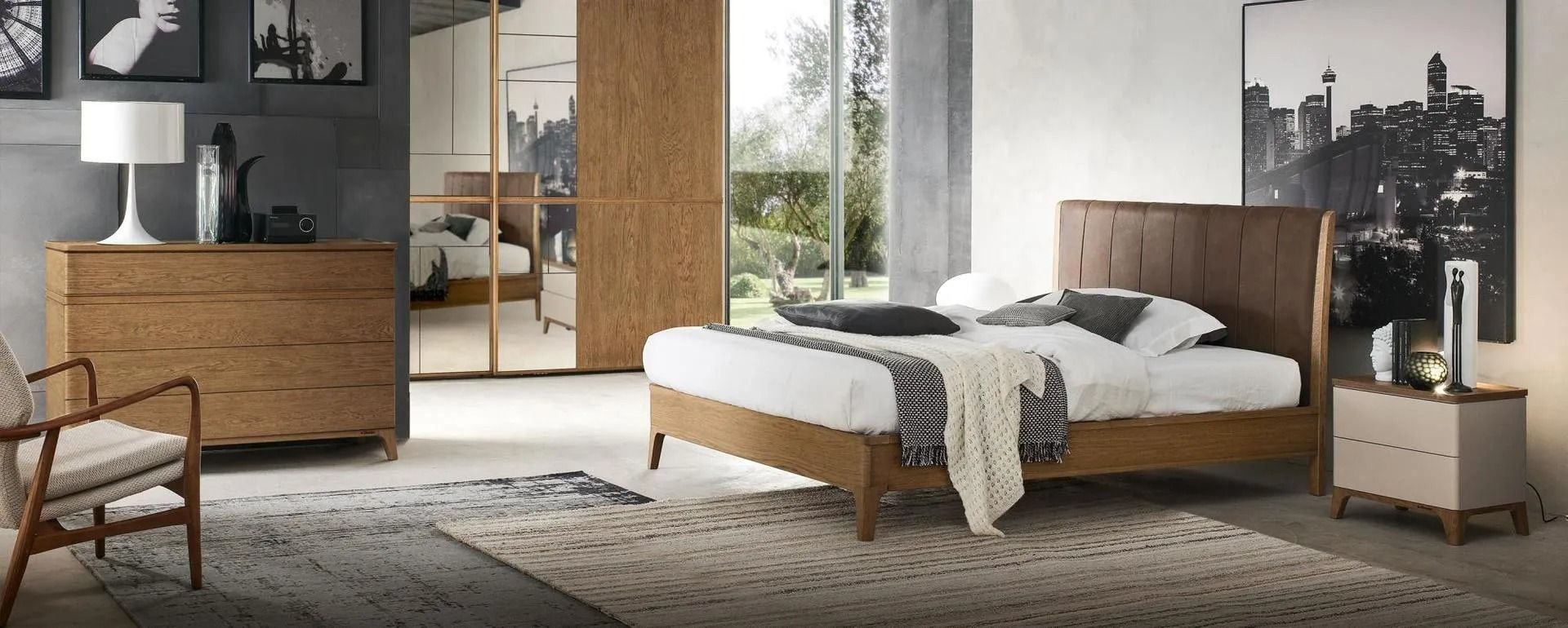 Una camera da letto con letto, cassettiera, sedia e grandi opere d'arte, con una combinazione di colori neutri.
