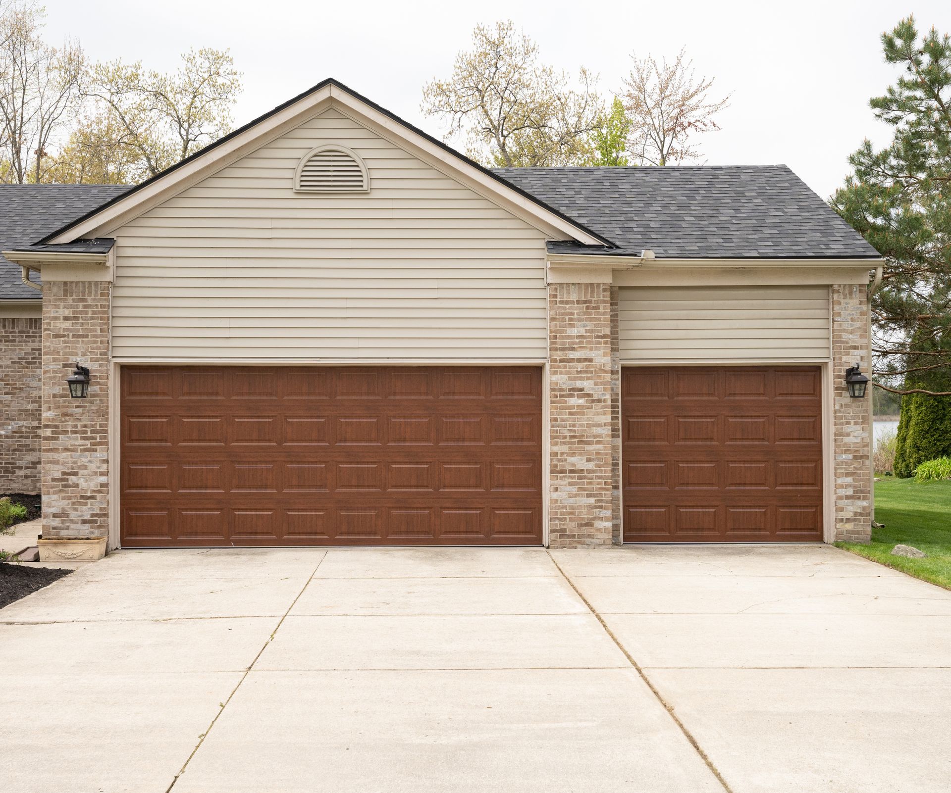 residential garage exterior featuring two brown paneled garage doors.