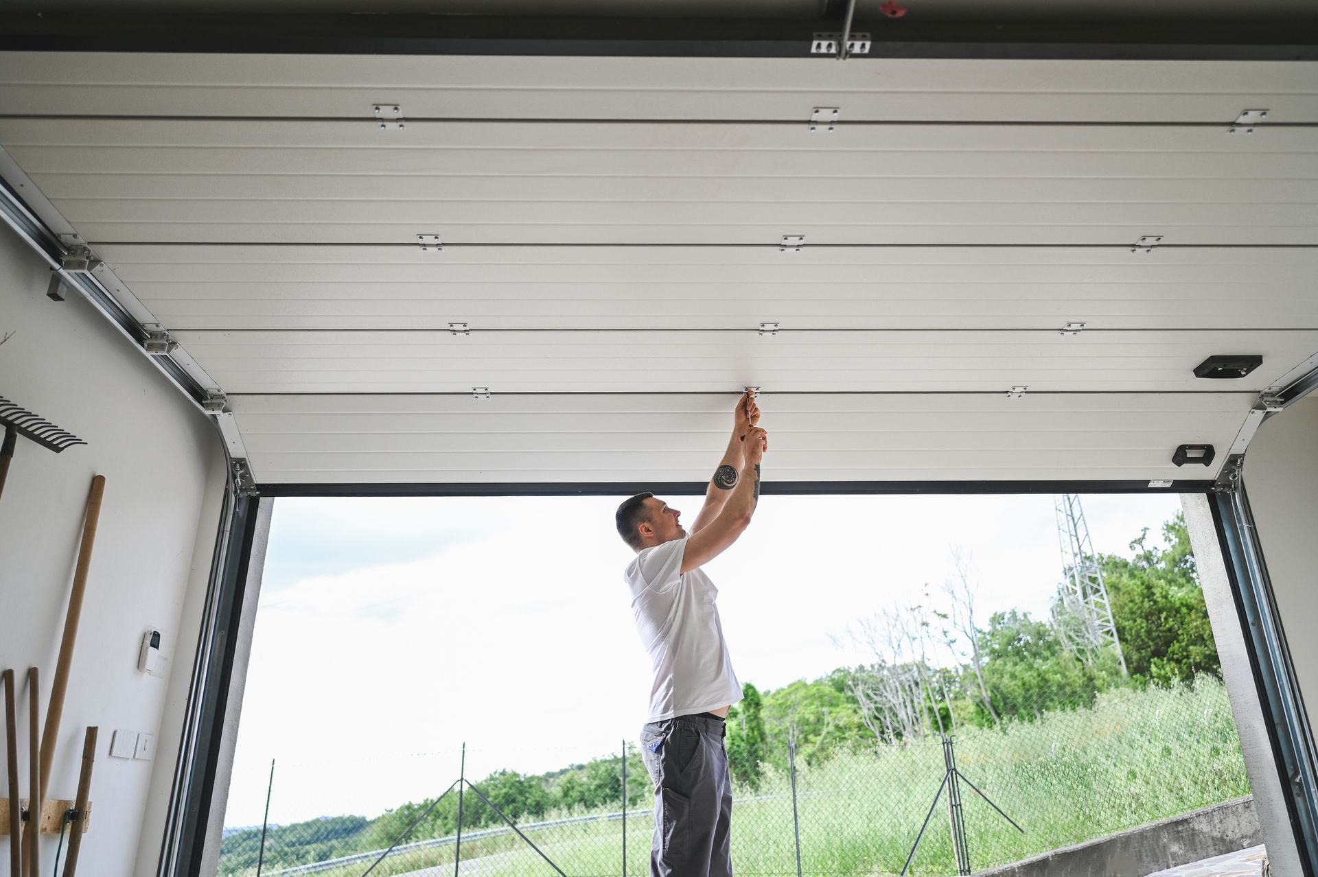 A man working on ceiling in garage, showcasing skills in garage door repair and home improvement.