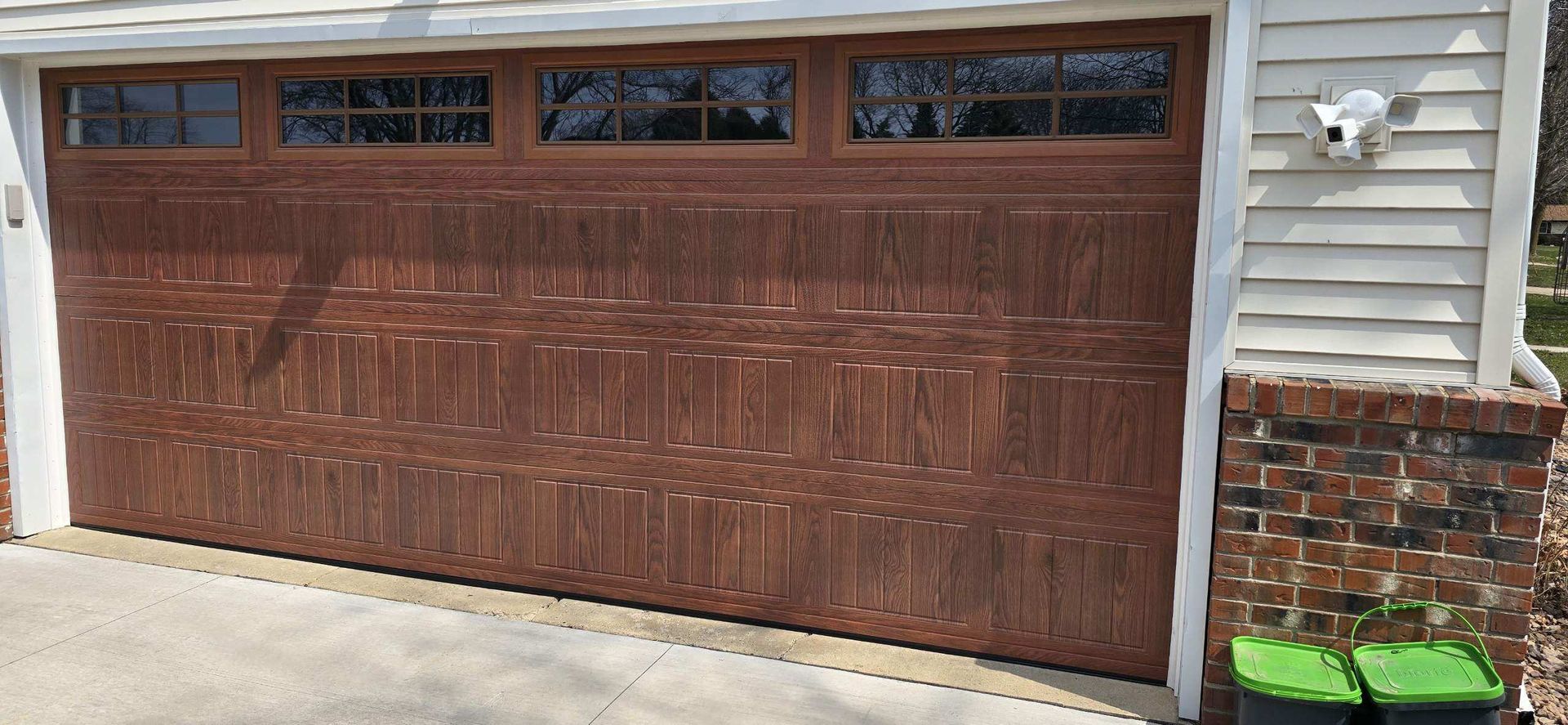 Brown double garage door on a house with small windows and light gray siding