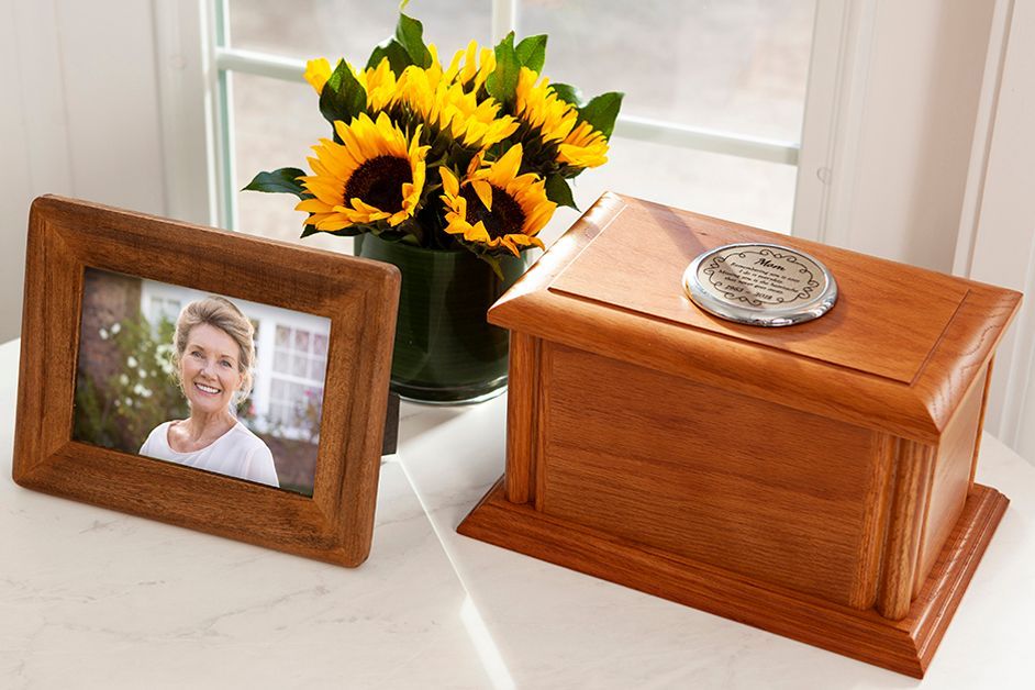 Wooden urn beside framed portrait and sunflower bouquet on a windowsill